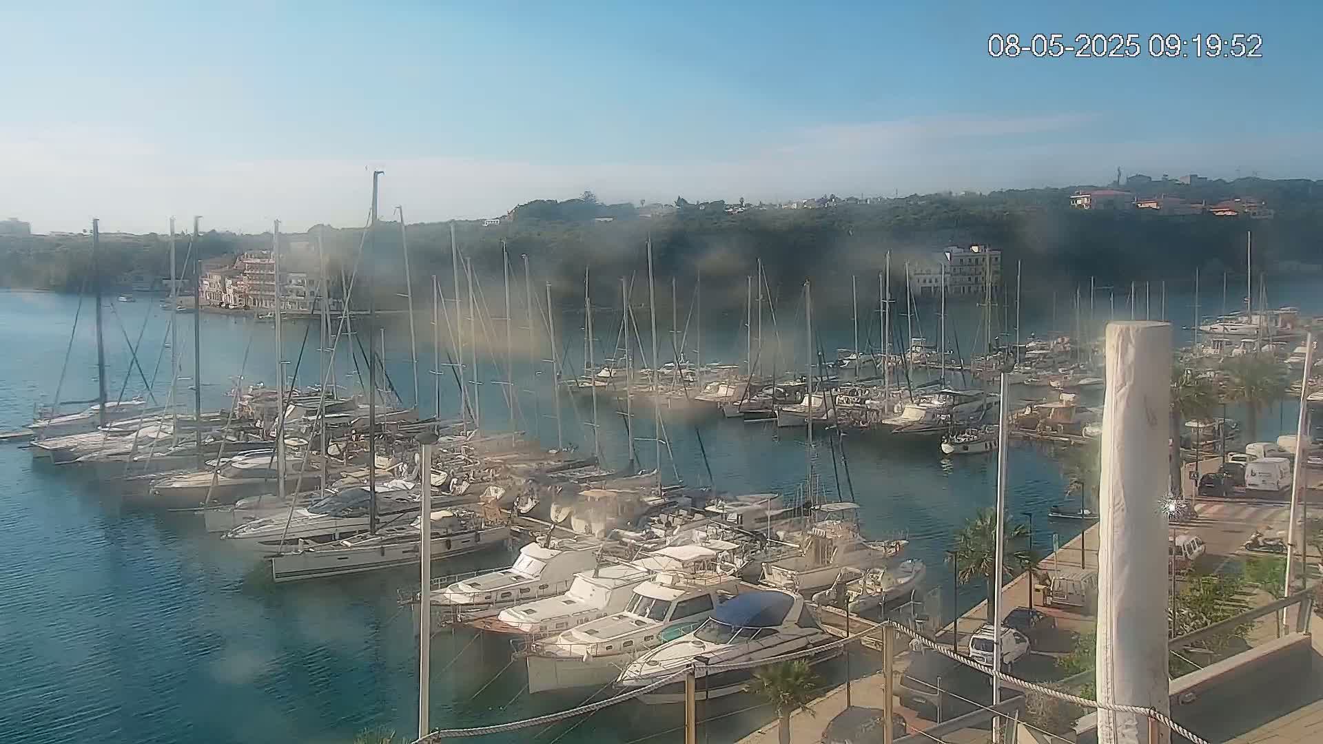 A marina filled with numerous sailboats and motorboats on a calm, sunny day.