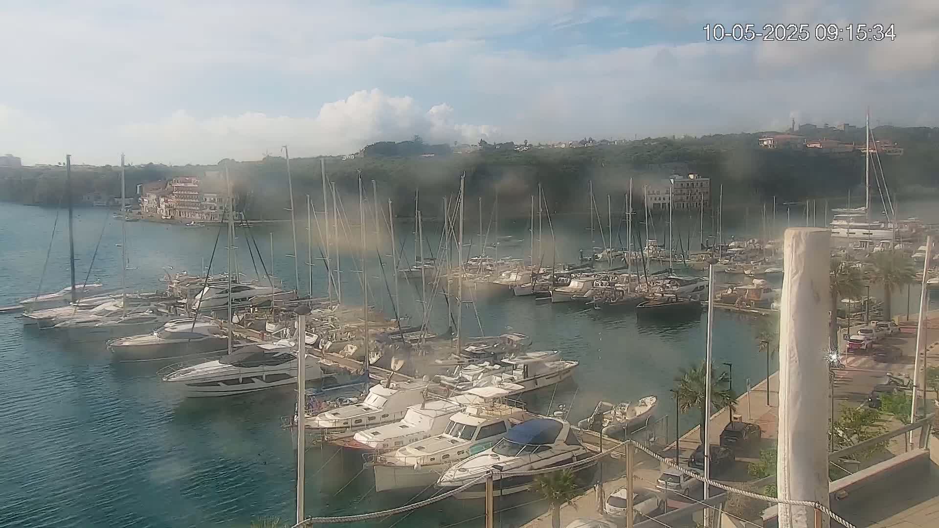 Many boats are docked in a marina on a partly cloudy day.