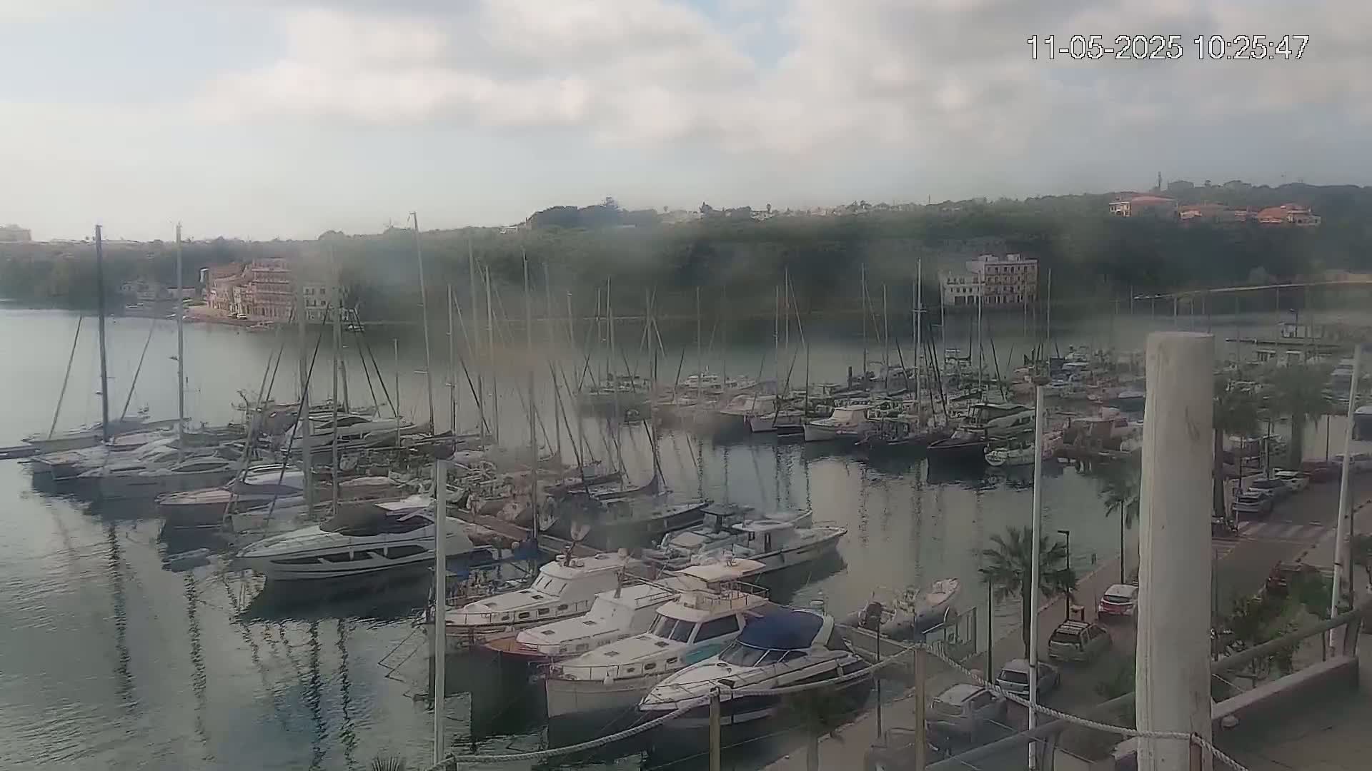 A marina filled with numerous sailboats and motorboats is seen on a cloudy day.