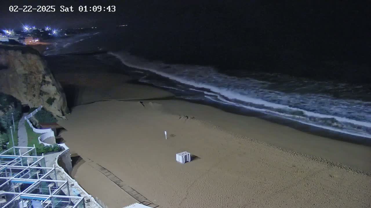 A sandy beach at night with waves rolling in under a dark sky.