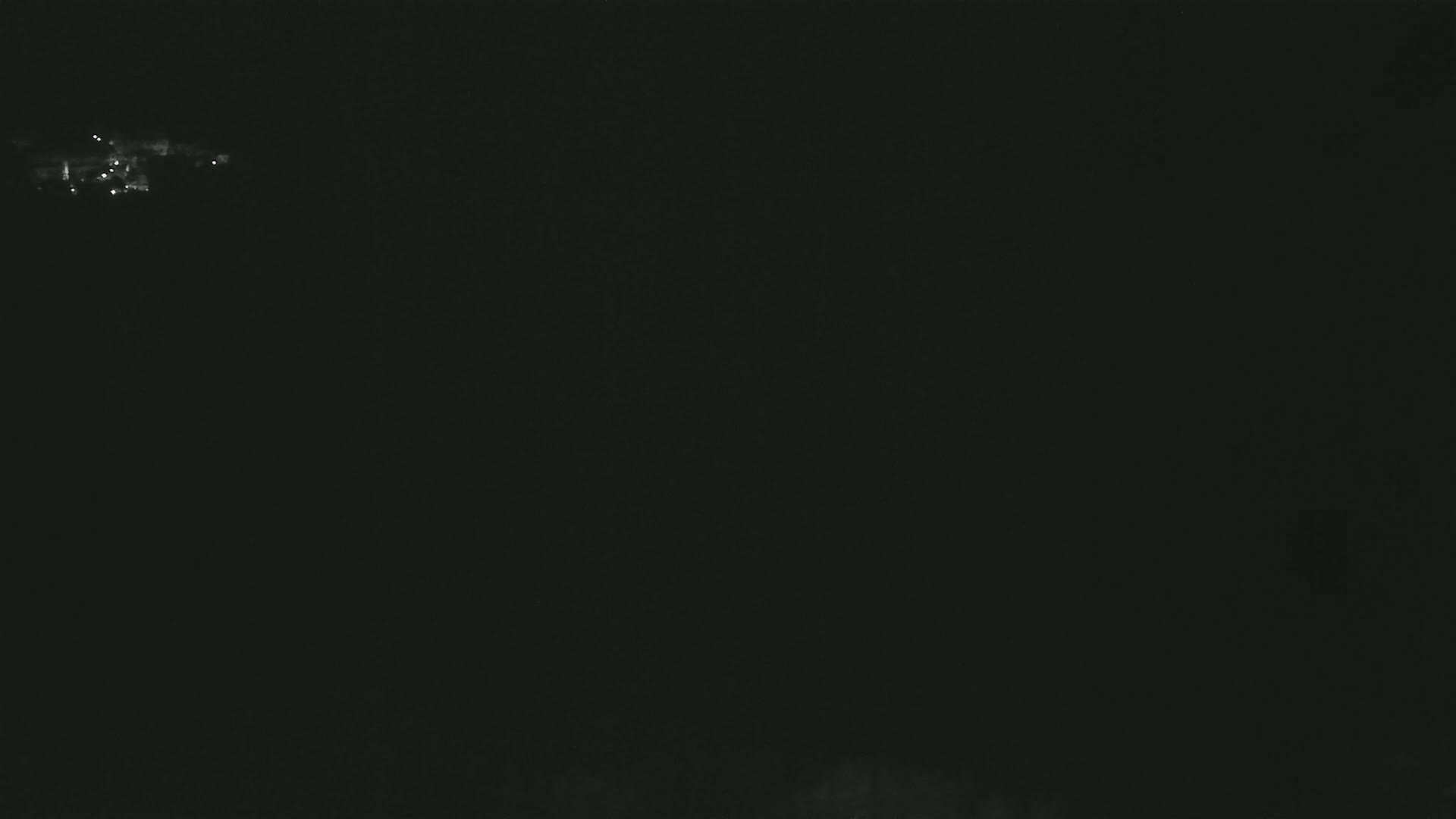 A small cluster of faint lights is visible in the distance against a dark, nighttime sky.