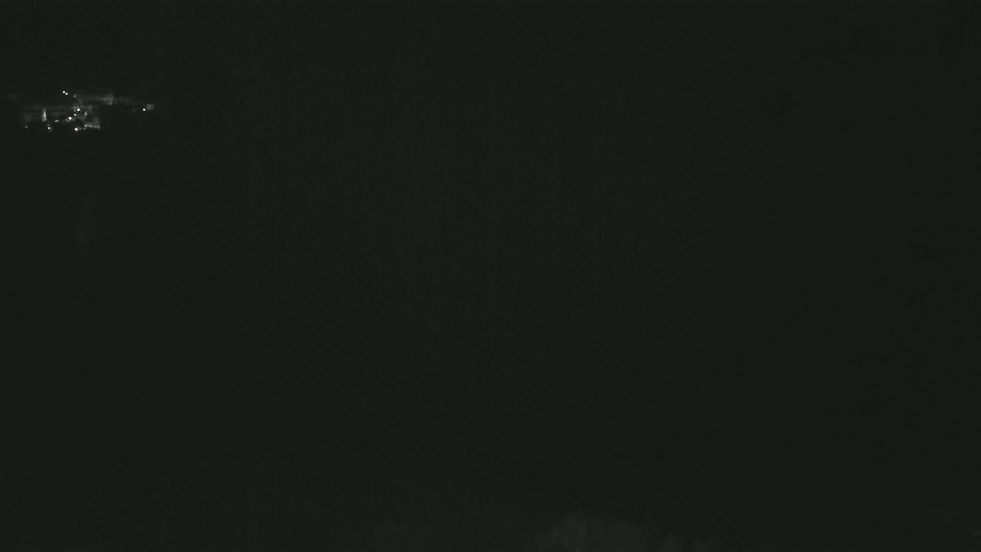 A nighttime, dark image shows a small cluster of faint lights in the distance.