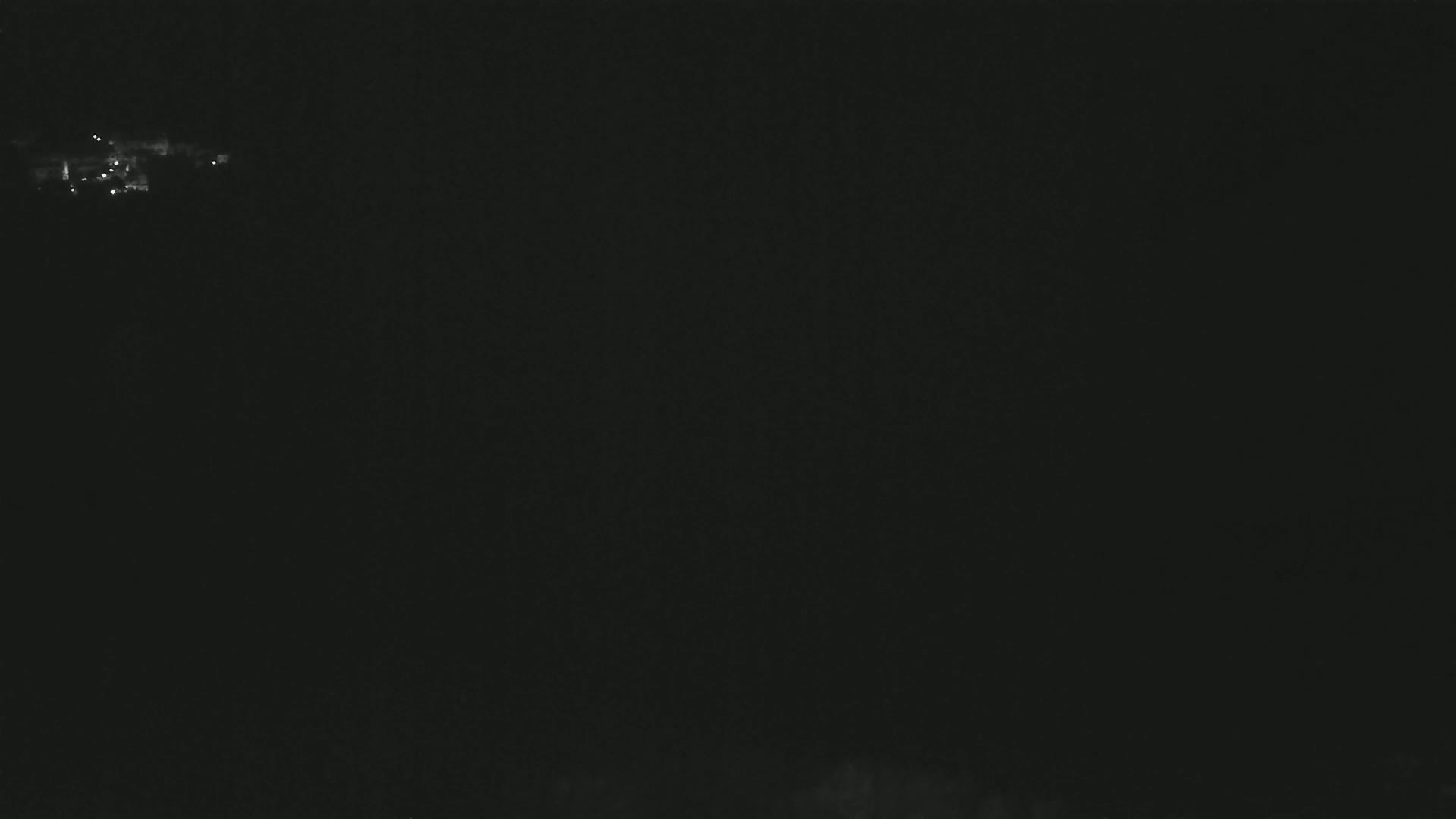 A dark, nighttime scene shows a few faint lights in the distance.