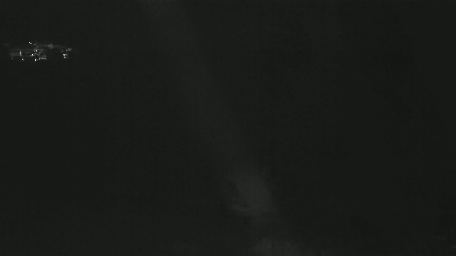 A dark, nighttime scene shows a faint light source in the distance and a beam of light cutting through the darkness.