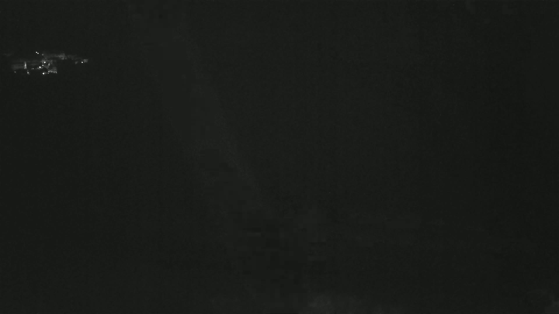 A dark, nighttime image shows a small cluster of distant lights at the top.