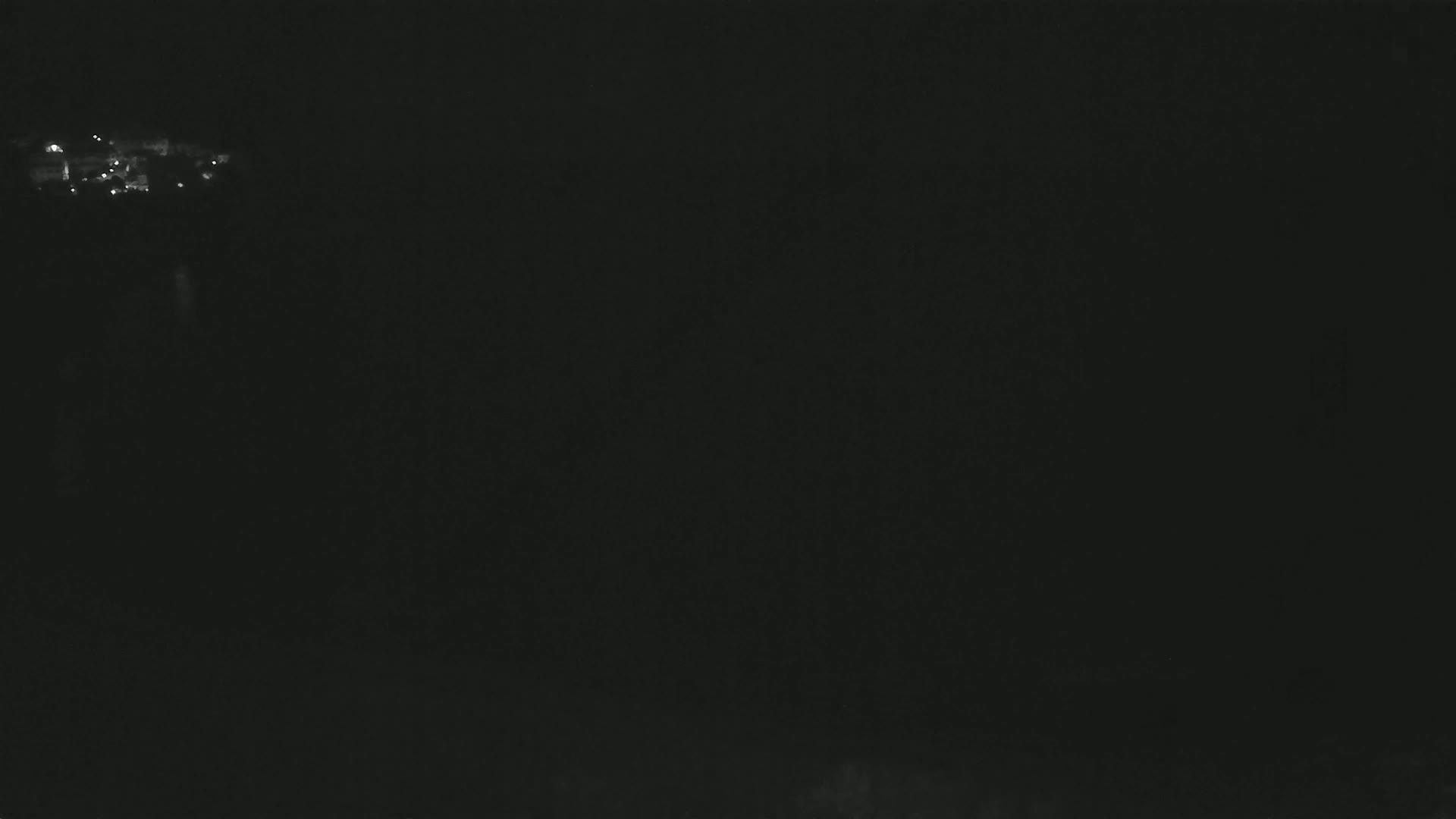 A dark, nighttime scene shows a few faint lights in the distance.