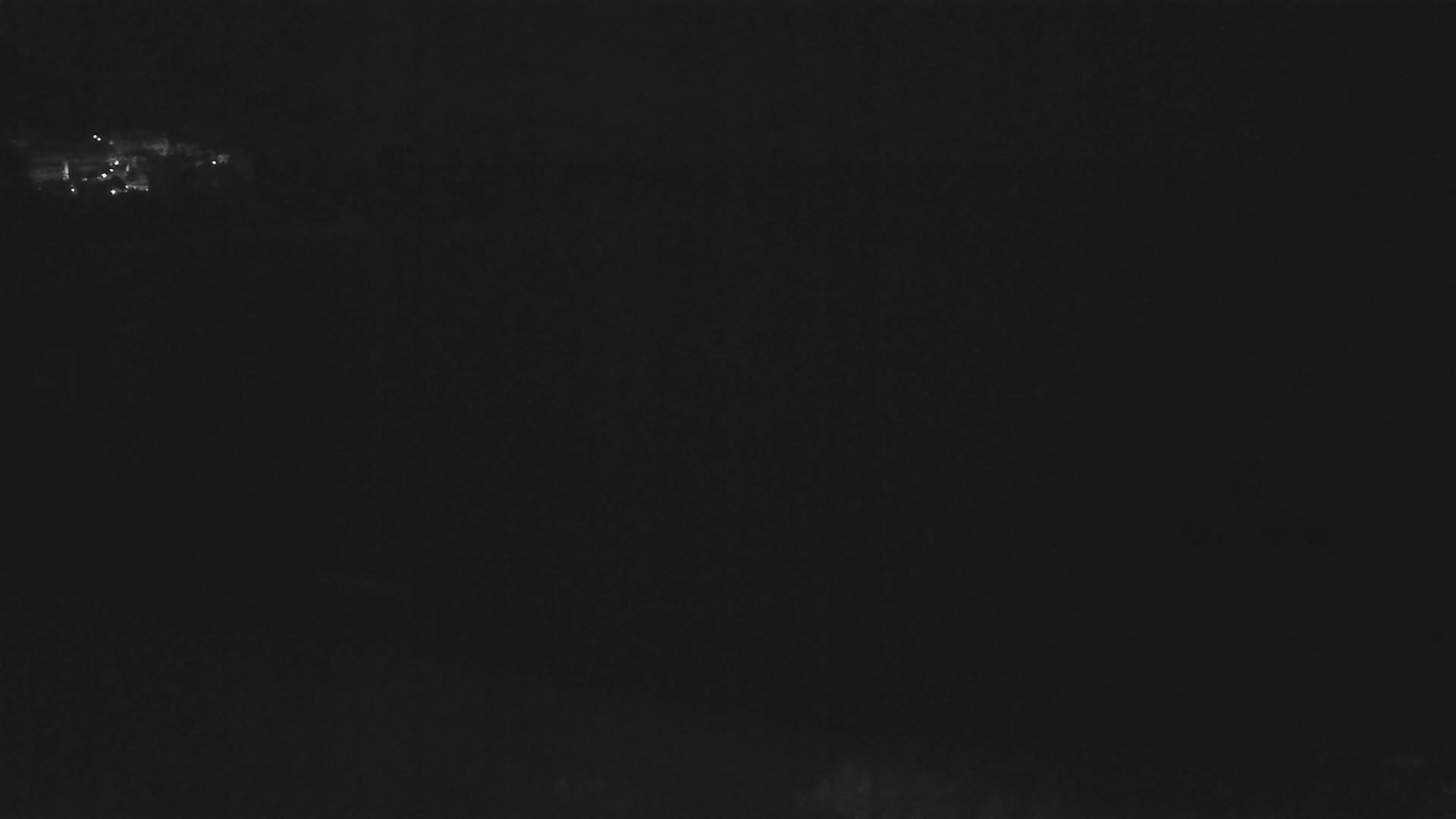 A dark, nighttime scene shows a few faint lights in the distance.