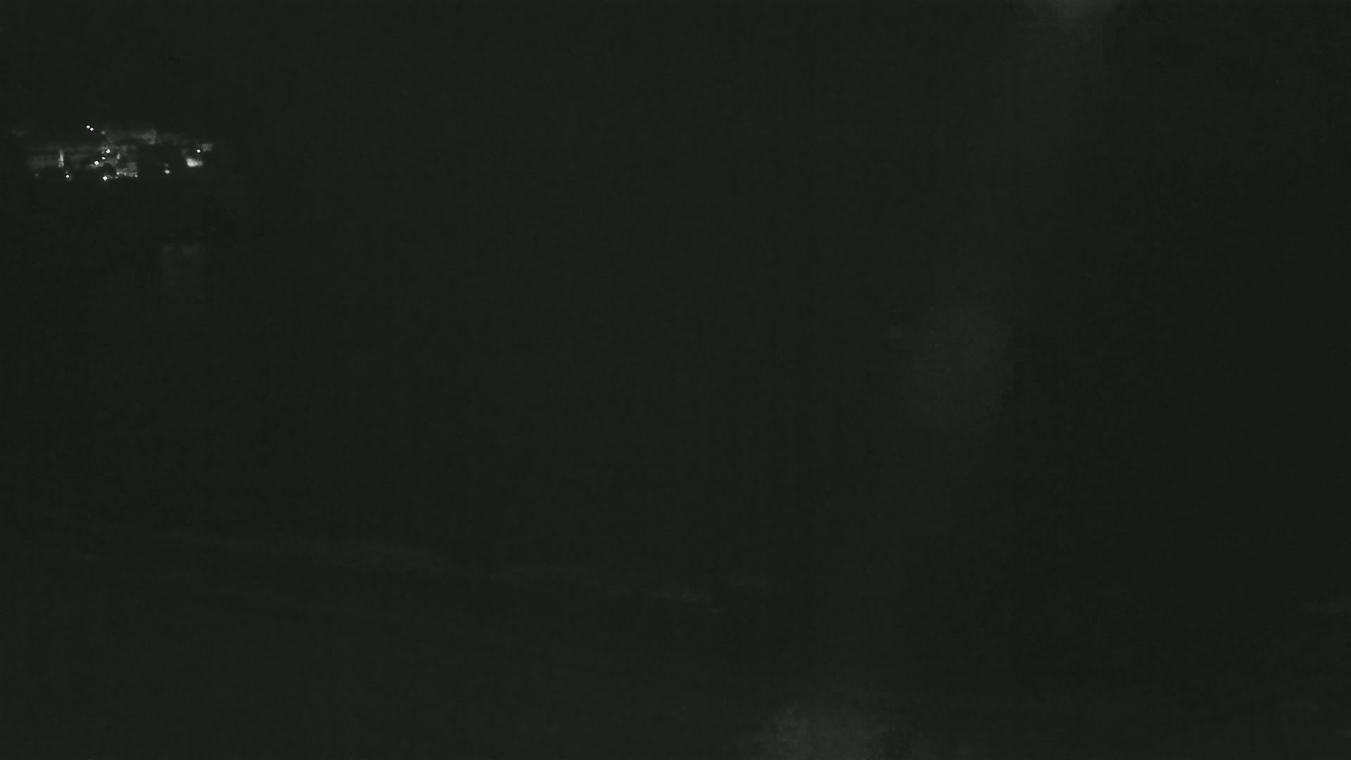 A dark, nighttime scene shows a few distant lights in the upper left corner.