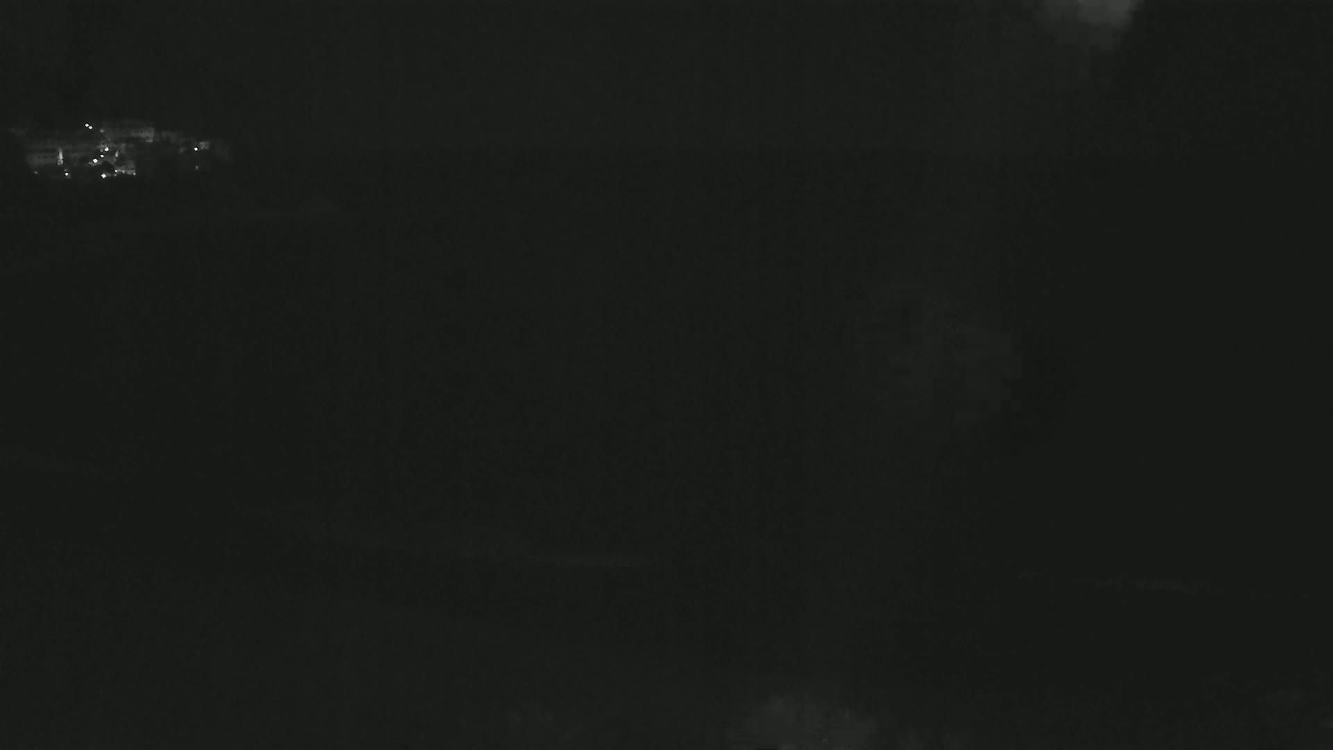 A dark, nighttime scene shows a few faint lights in the distance.