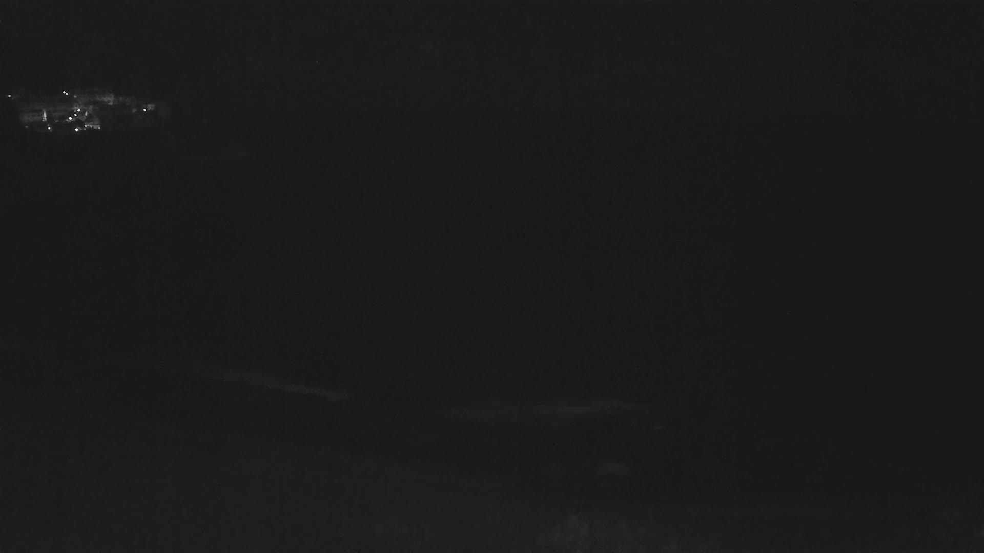 A dark, nighttime scene shows a dimly lit area in the distance.