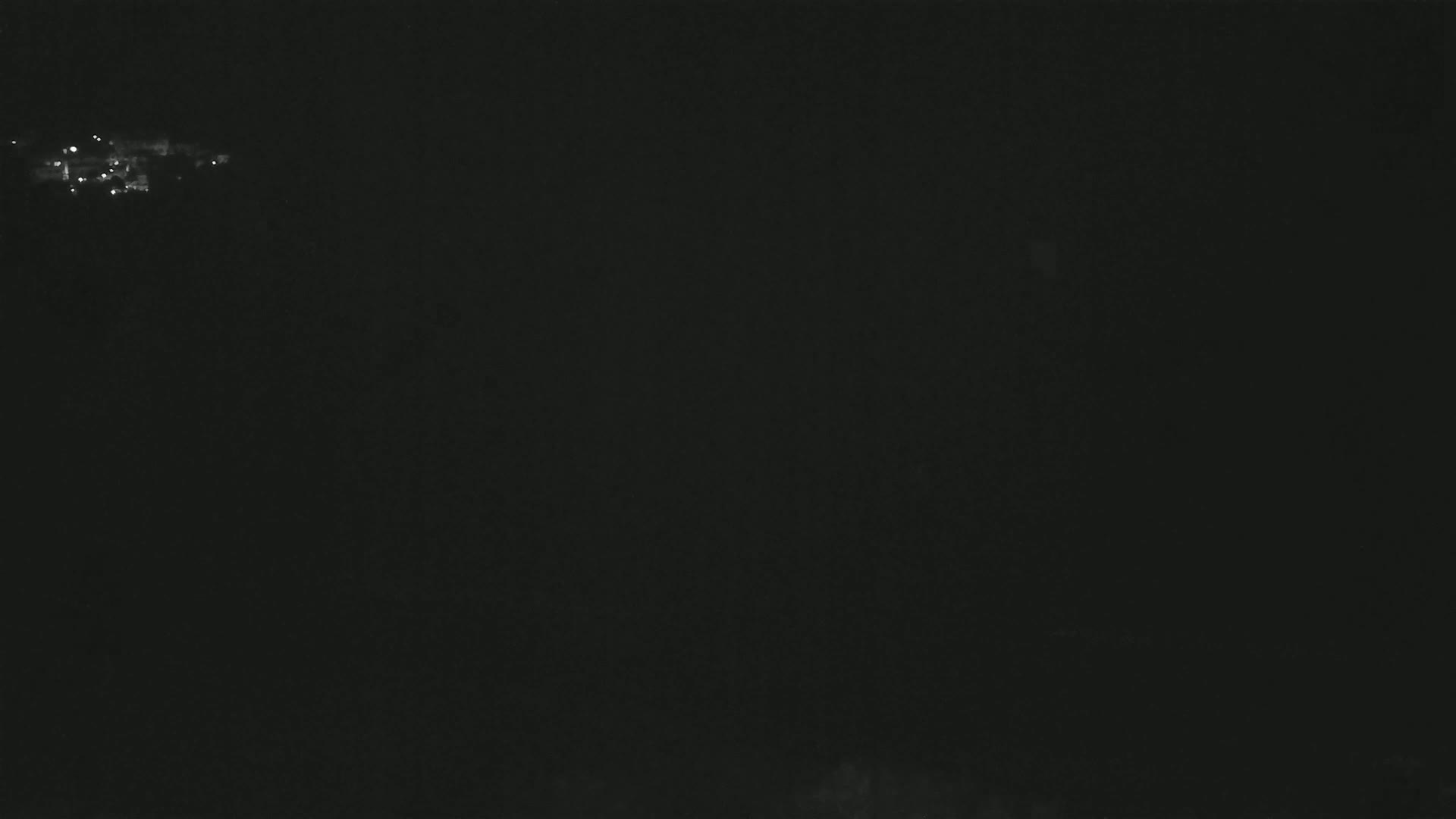 A nighttime view shows a distant, faintly lit town or city under a dark, possibly cloudy sky.