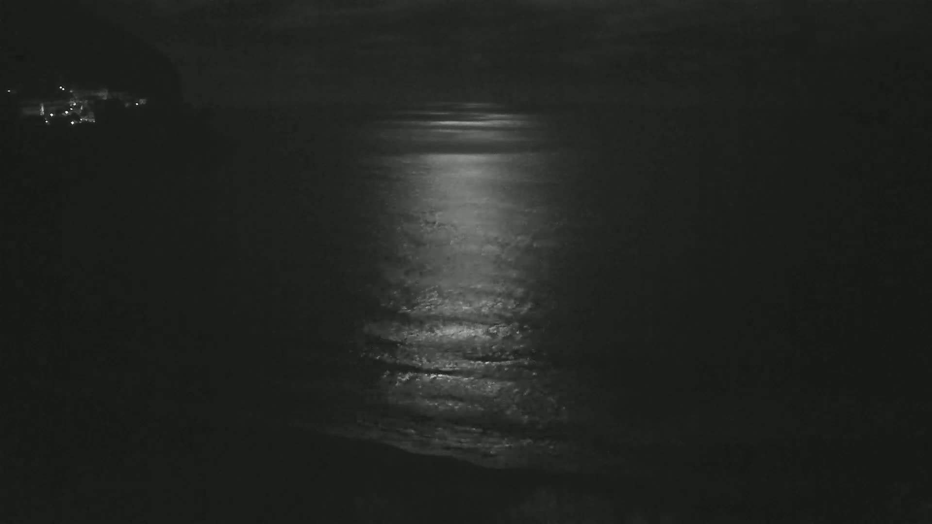 A moonlit ocean reflects a bright path of light onto the dark water at night.