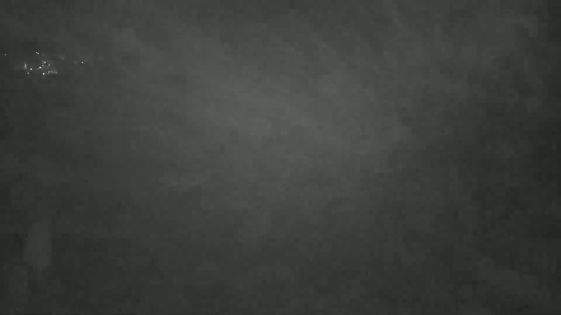 A dark, hazy night scene shows faint lights in the distance.