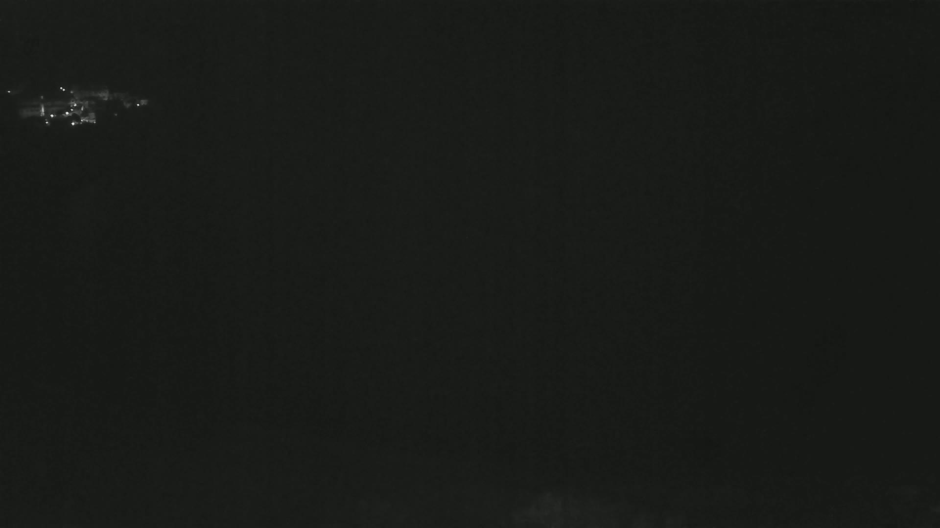 A nighttime, long-distance view shows a few faint lights in the far distance.