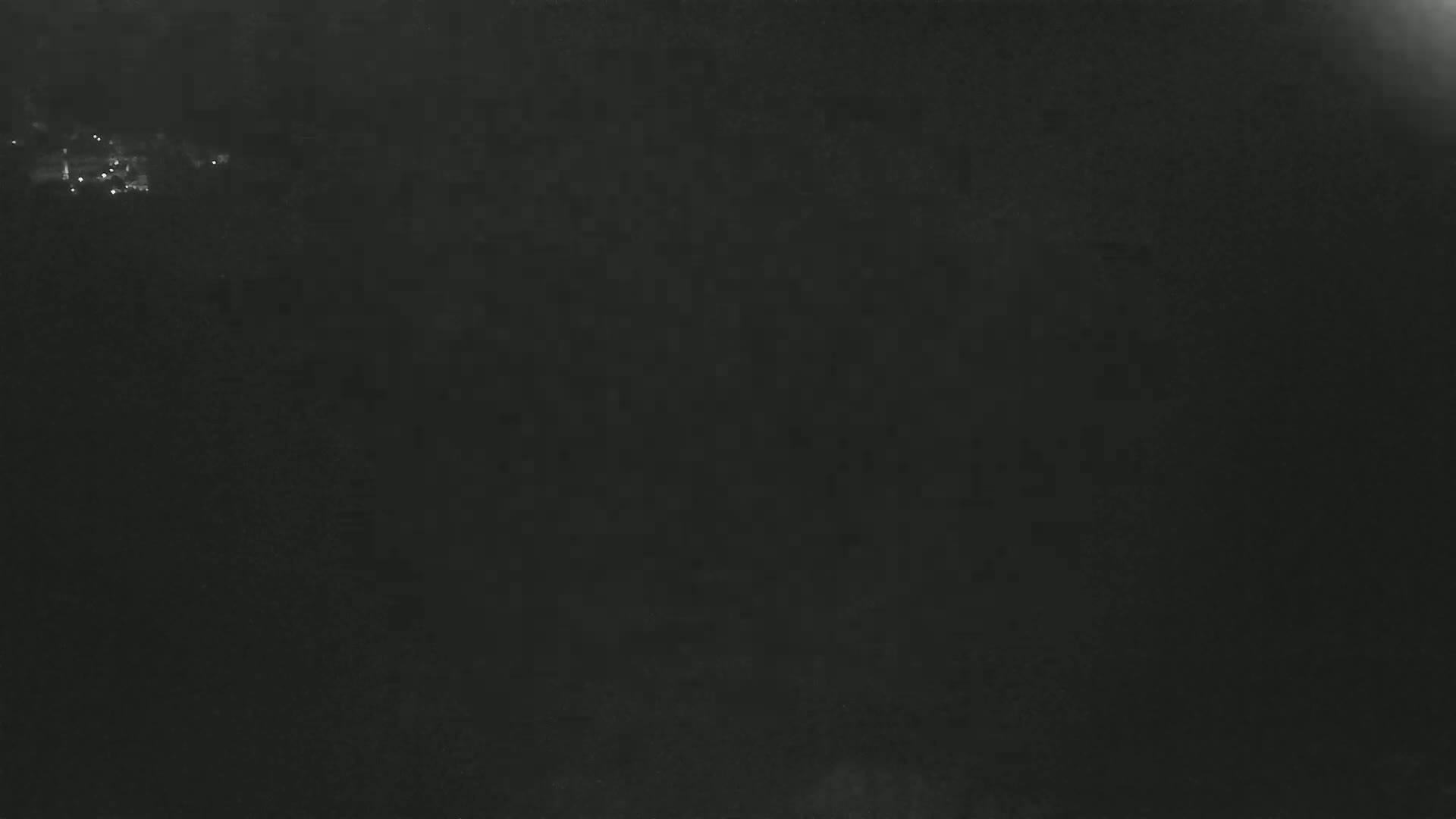 A blurry, dark nighttime image shows a faint scattering of distant lights.