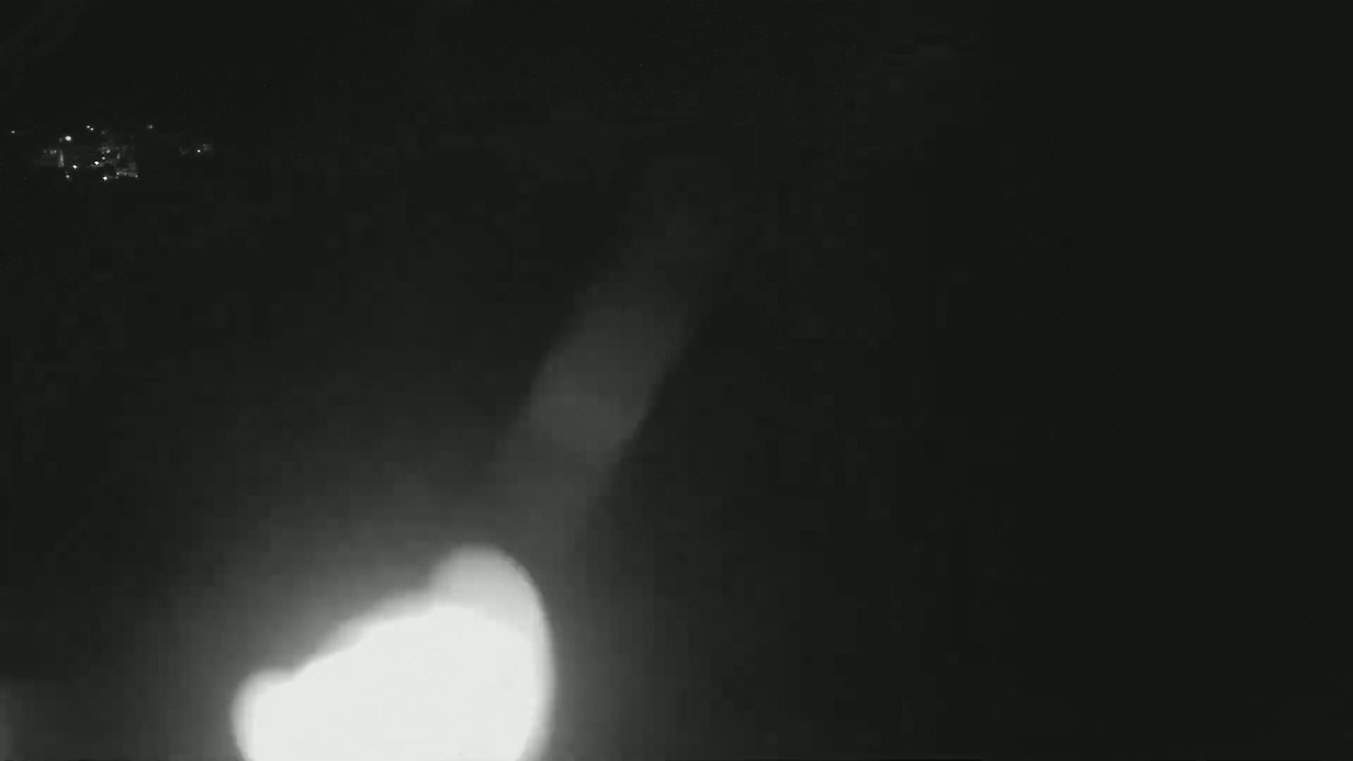 A bright light source is visible through a hazy, dark atmosphere at night.