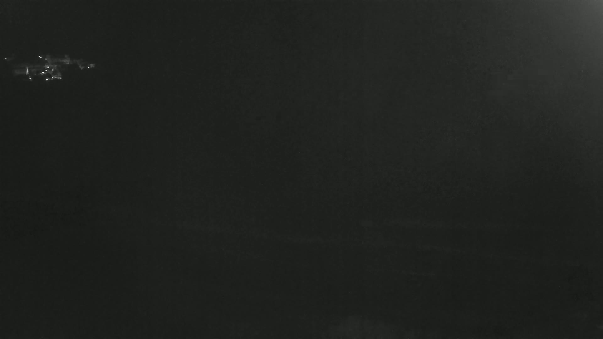 A dark, nighttime scene shows a few distant lights in the upper left corner.