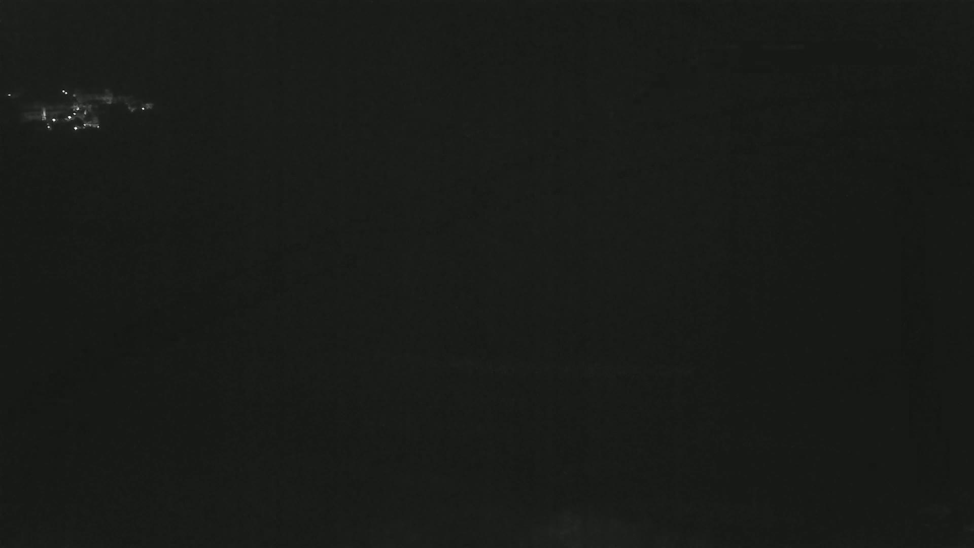 A mostly dark image shows a few faint lights in the distance at night.