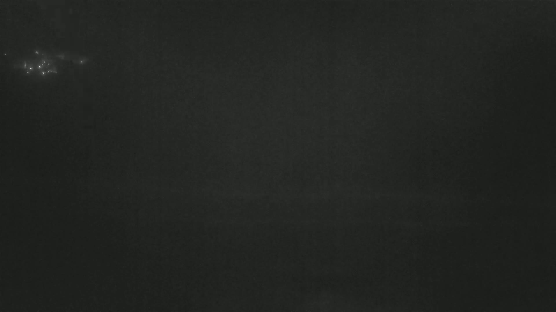 A dark, possibly nighttime, scene shows a few faint, distant lights in an otherwise mostly black sky.