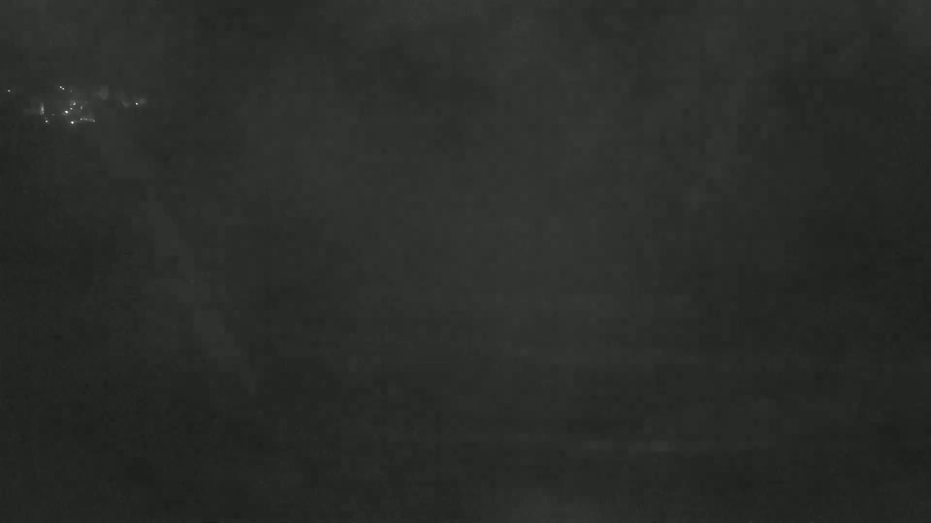 A dark, blurry image shows faintly lit lights in the distance on a foggy night.