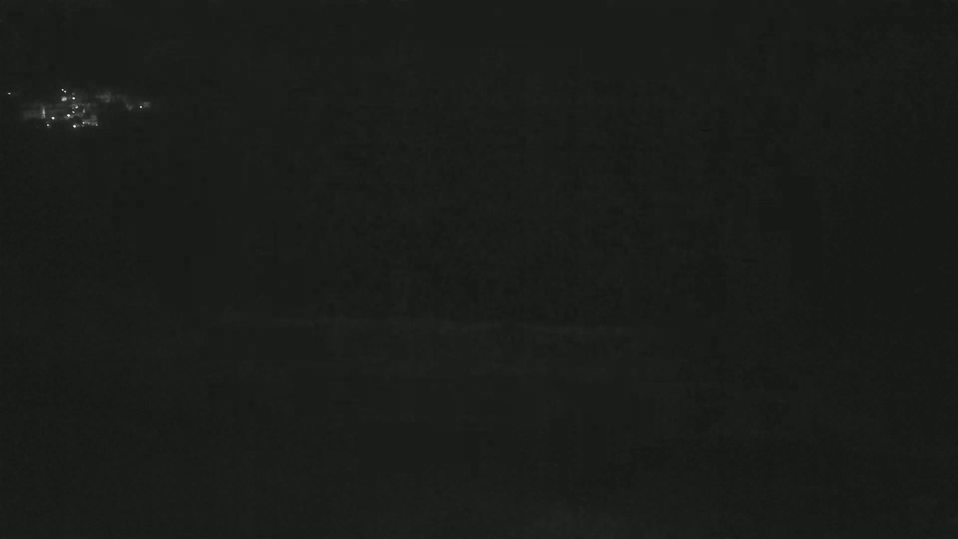 A nighttime, dark scene with a few faint lights visible in the distance.