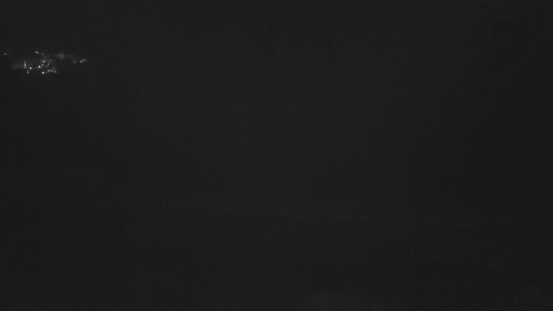 A dark, nighttime scene shows a few faint lights in the distance.