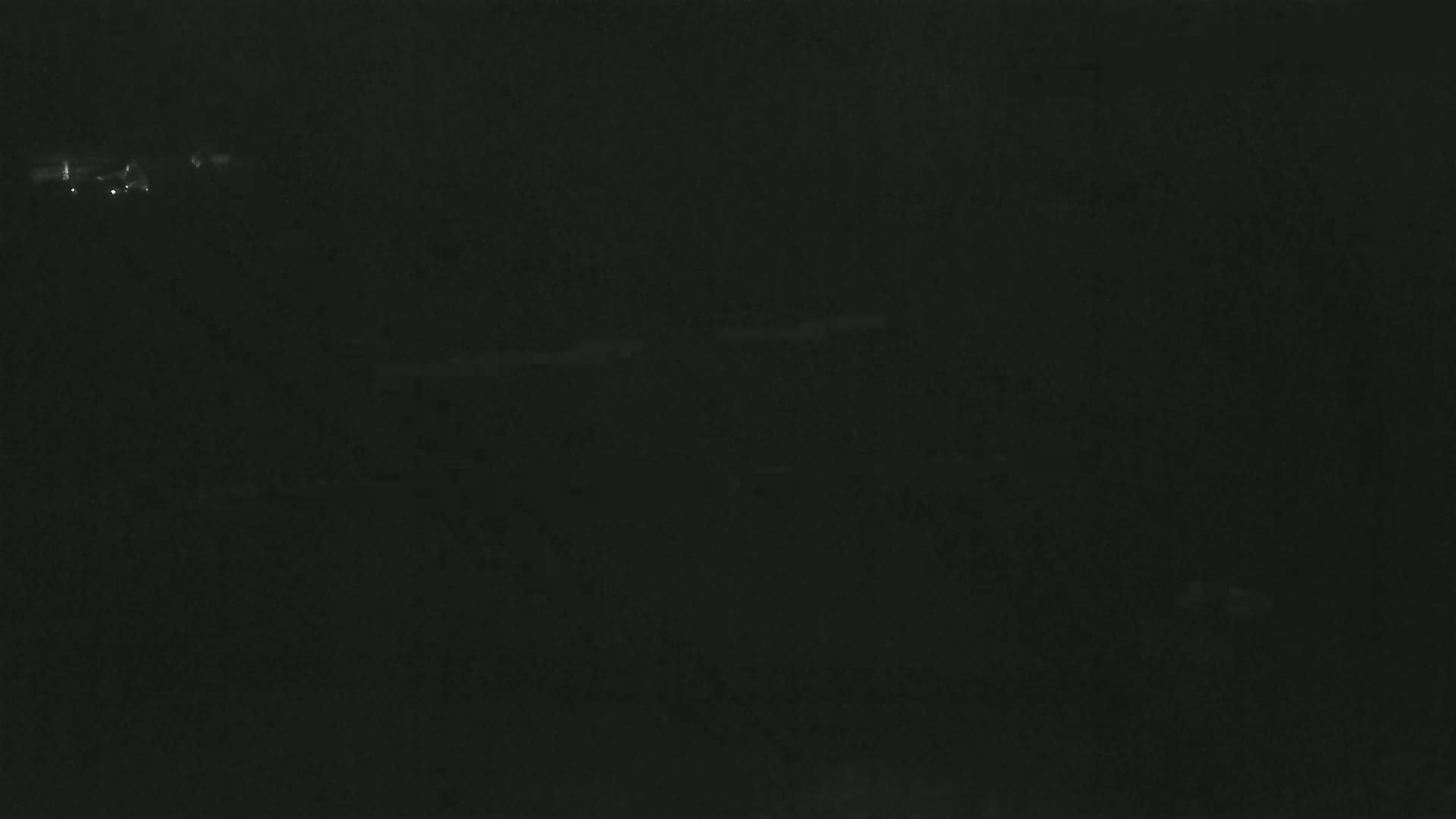 A dark, nighttime scene shows a few faint lights in the distance.
