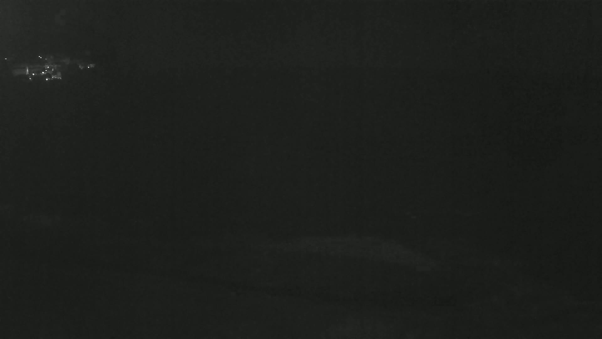 A dark, nighttime scene shows a few distant lights in the upper left corner.