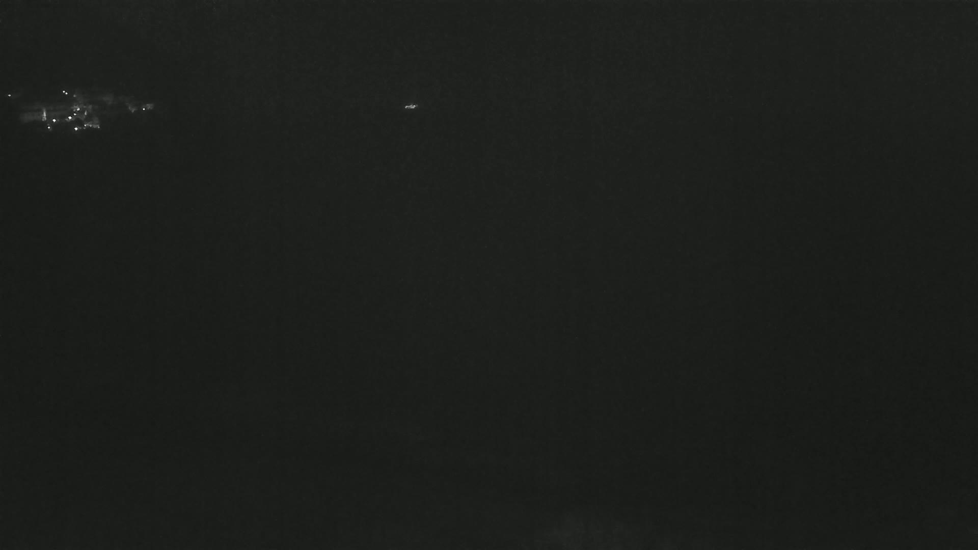 A dark, nighttime scene shows a few faint lights in the distance.