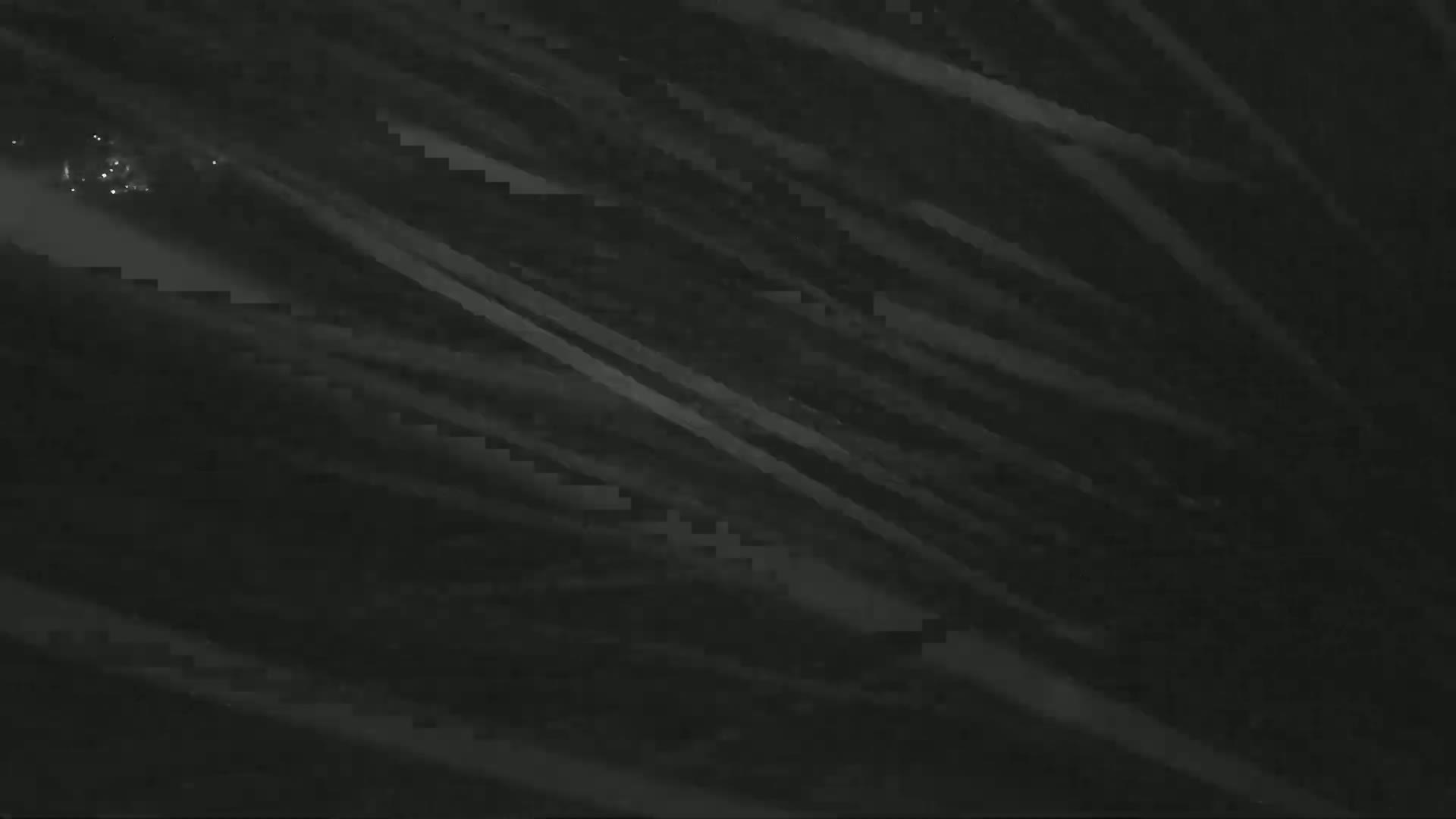 A dark, blurry image shows diagonal streaks of light against a black background.