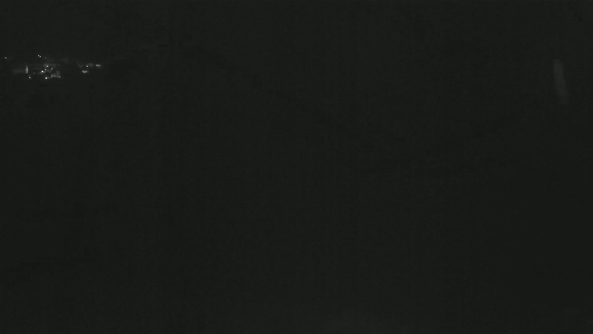 A dark, nighttime scene shows a distant collection of faint lights.