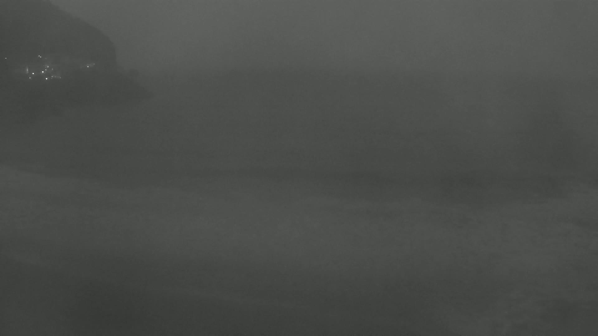 A foggy, dark landscape is visible, with faint lights in the distance to the left.