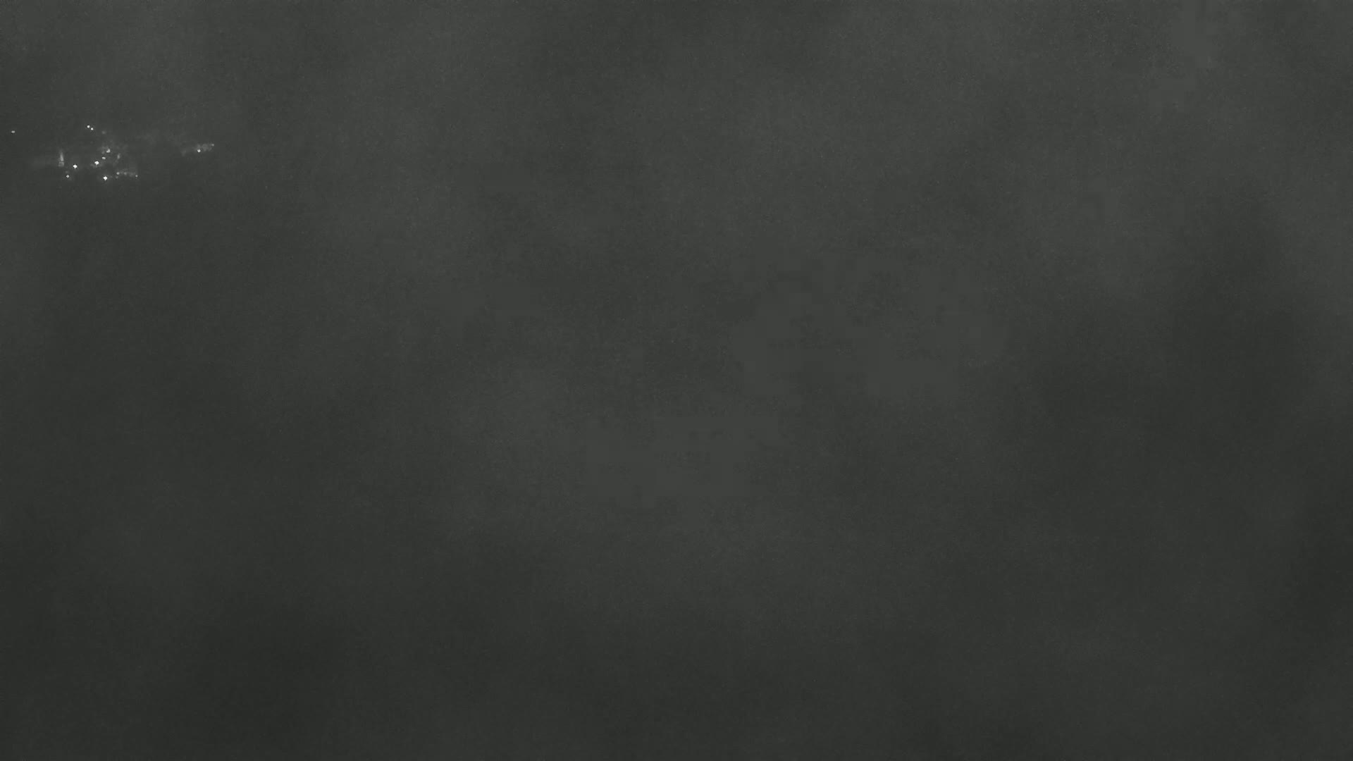 A dark gray or black textured background with a few faint, brighter specks near the top.