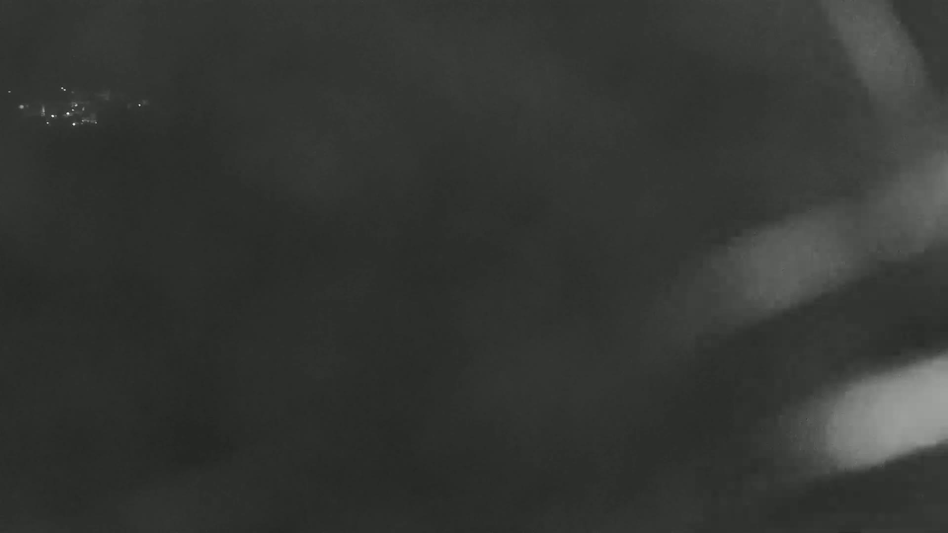 A blurry, dark image shows a few faint lights in the distance on a hazy night.