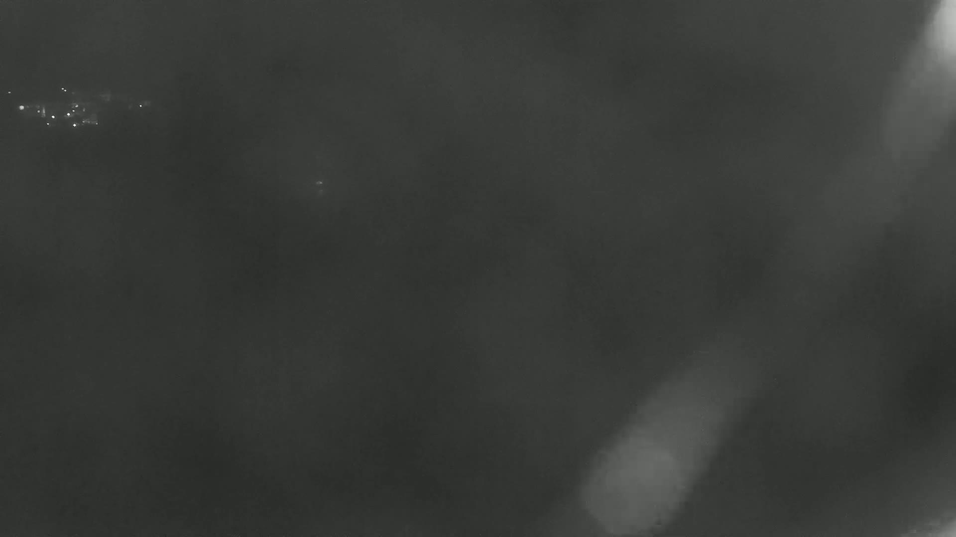 A hazy, dark gray outdoor scene shows indistinct lights in the distance.