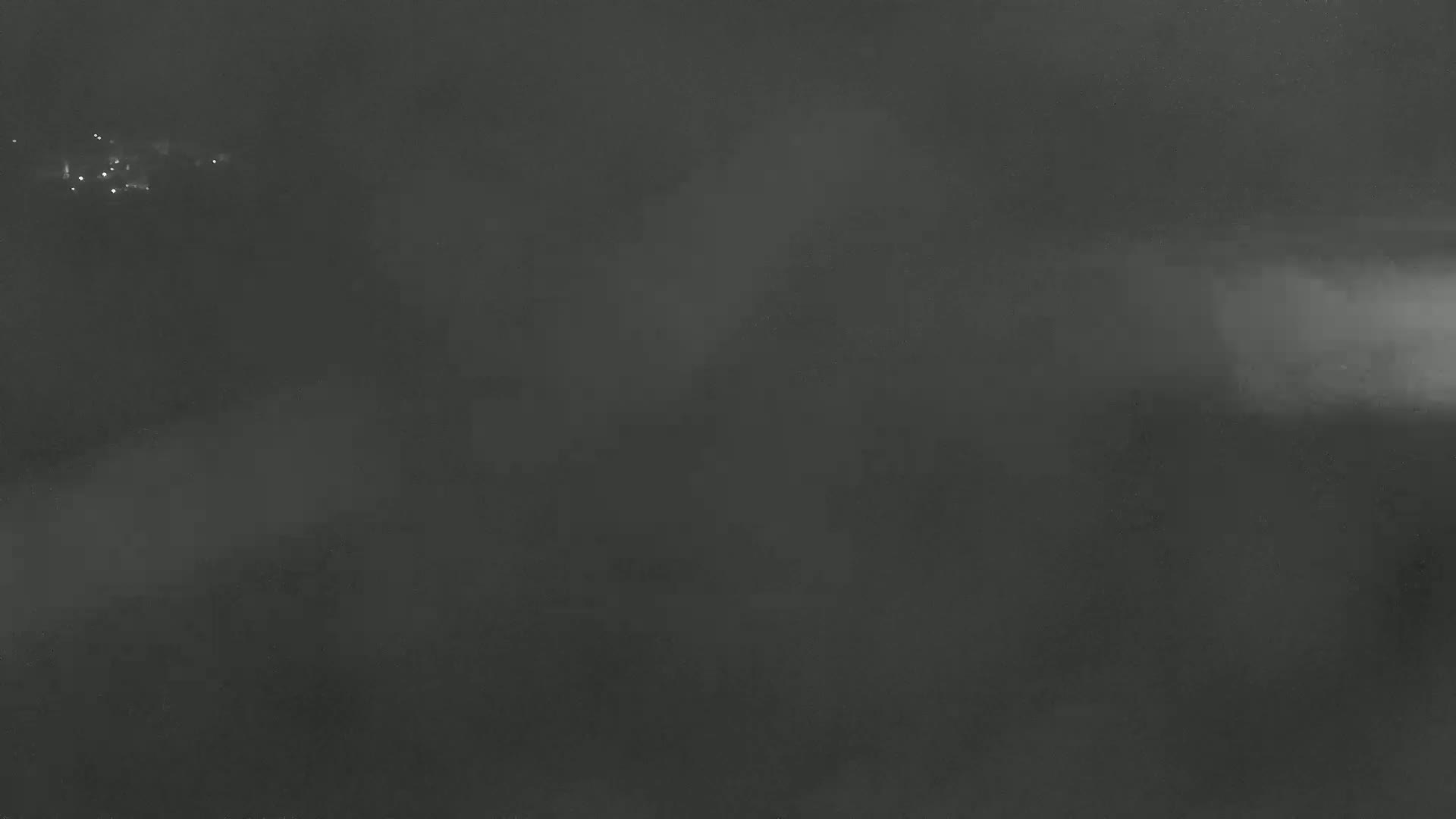 A dark, foggy scene is visible with a few faint lights in the distance.