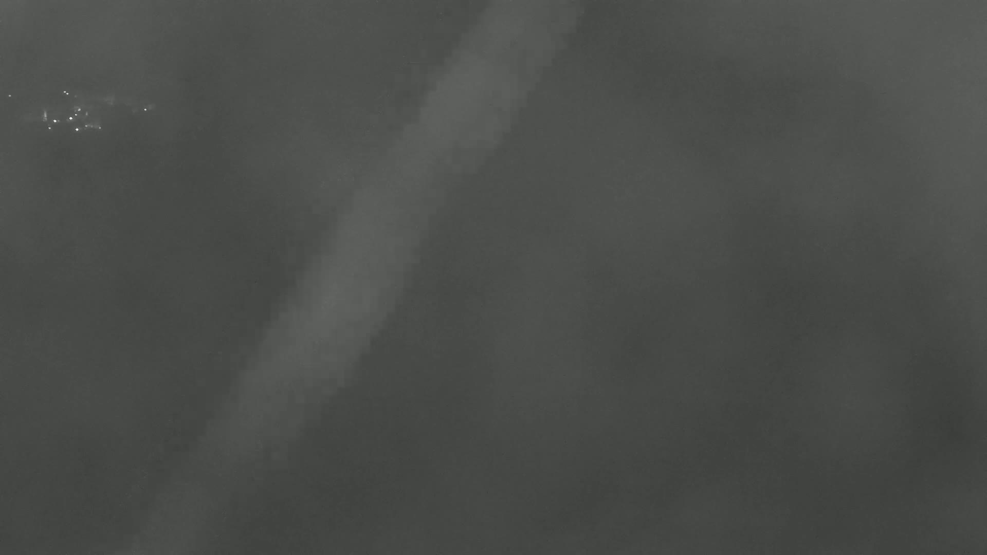 A faint, bright streak appears in a dark, foggy sky.
