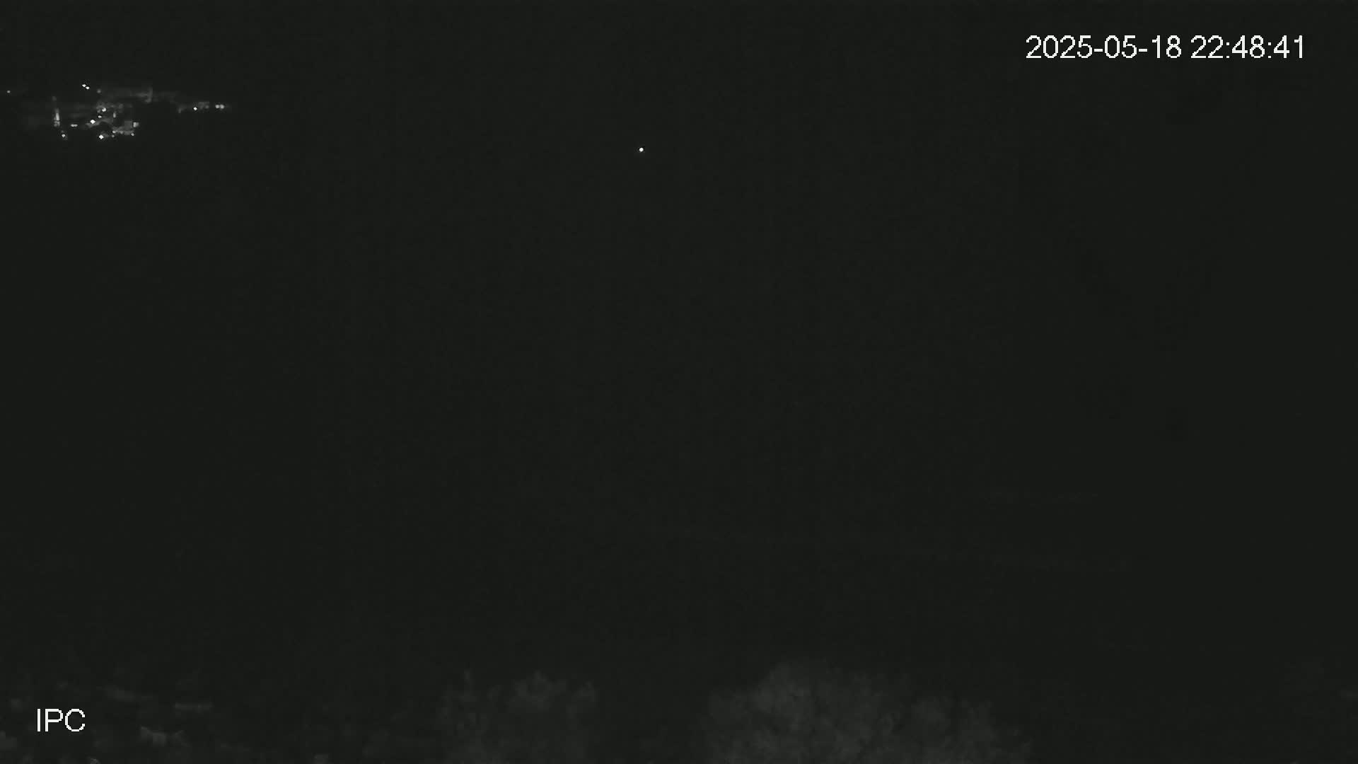 A nighttime long shot shows a dark landscape with a few distant lights and a single bright light in the sky.