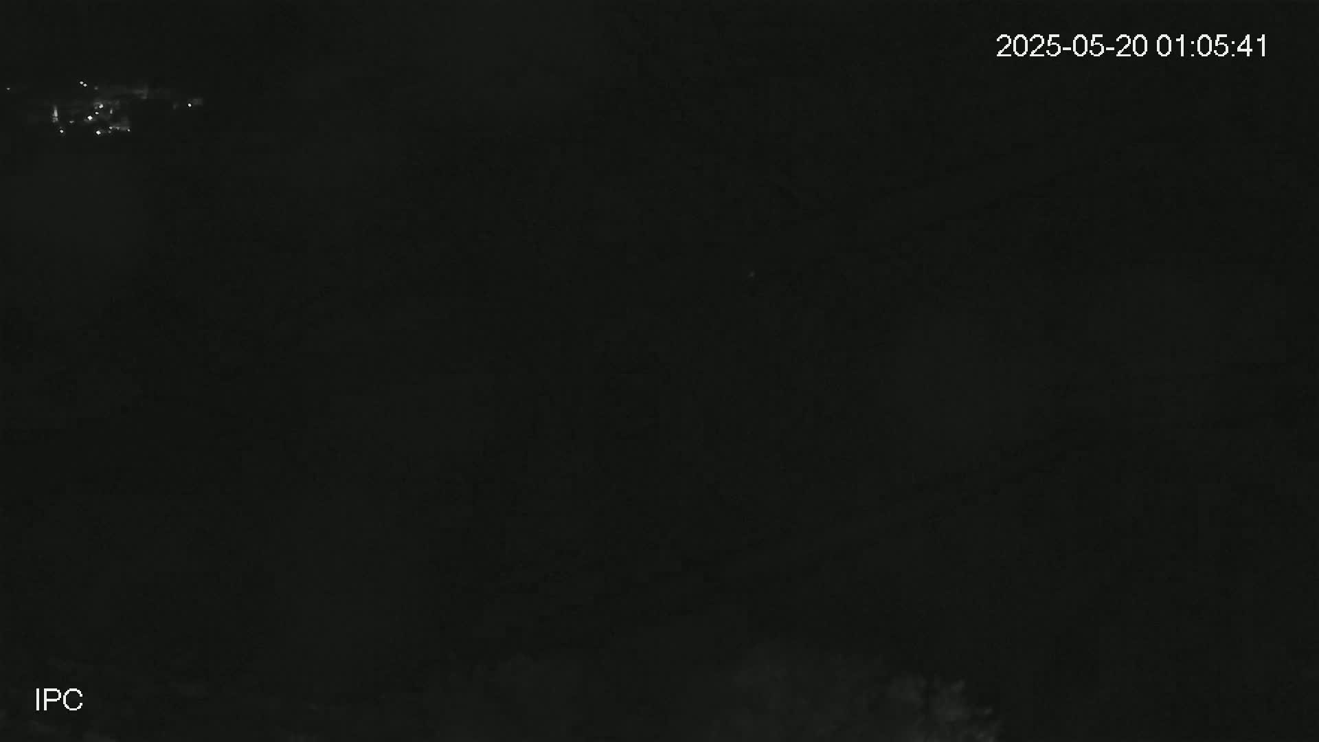 A nighttime, low-light image shows a dark, possibly overcast sky with a few faint lights visible in the distance.