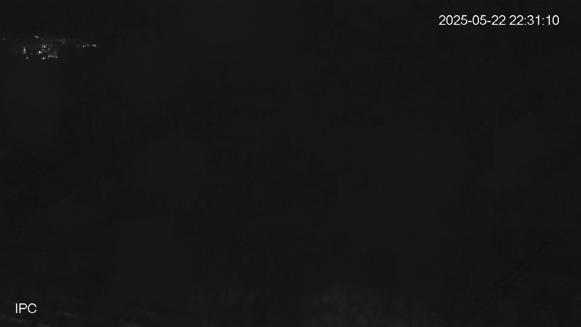 A dark, nighttime image shows a faint line of distant lights in the upper left corner.