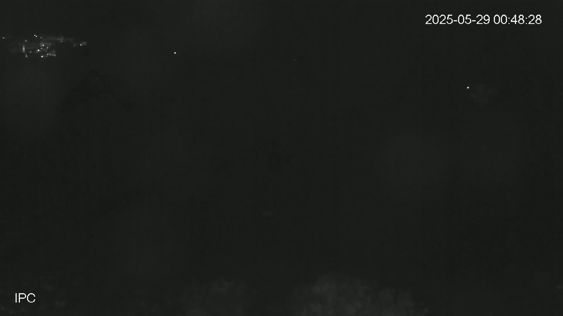 A nighttime outdoor scene shows a dark sky with a few faint lights in the distance.