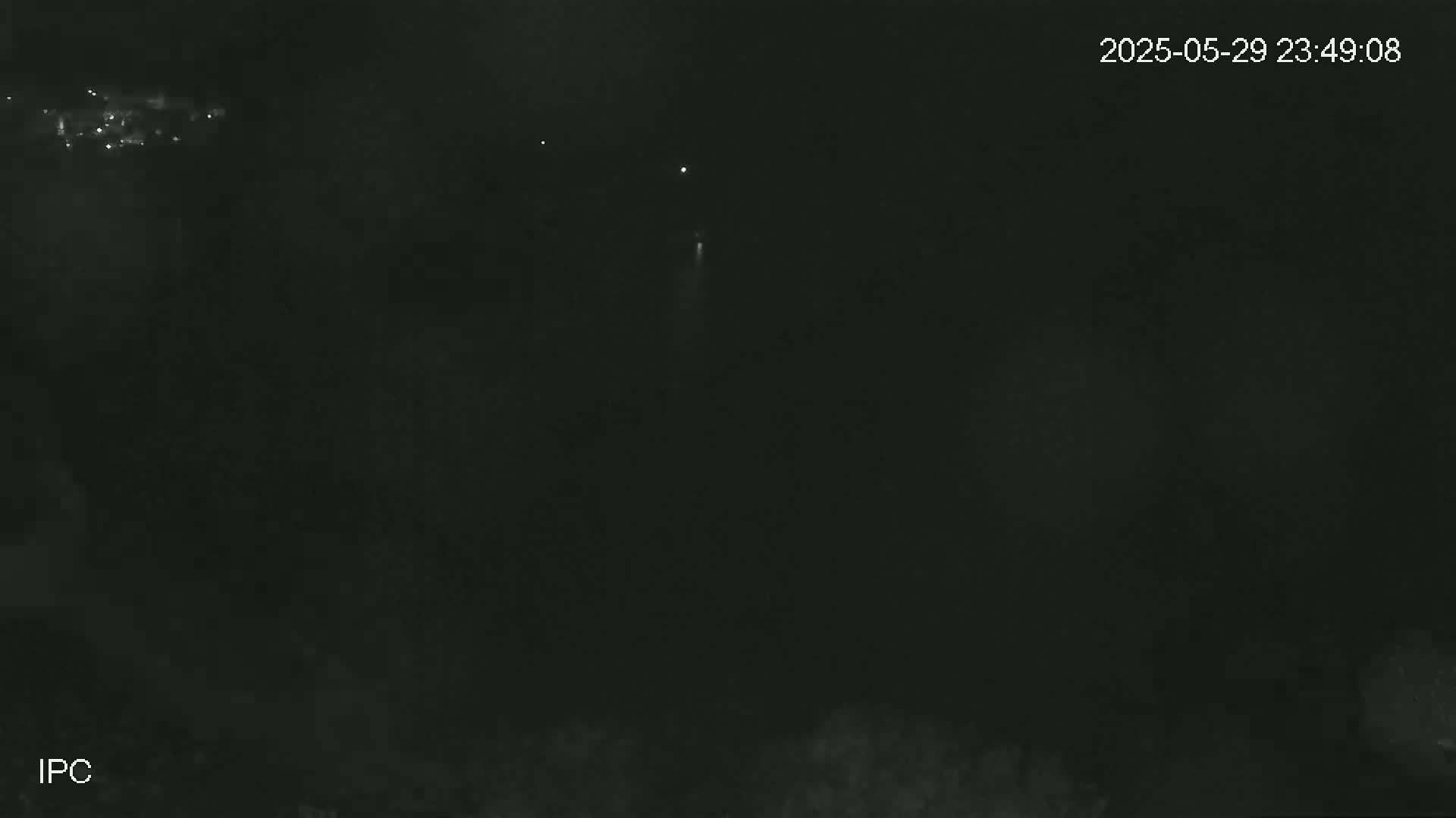 A nighttime outdoor scene shows a dark sky with a few faint lights in the distance.