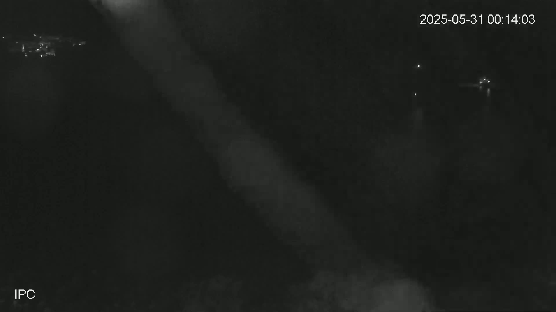 A nighttime, low-light image shows a hazy, blurry scene with faint lights visible in the distance.