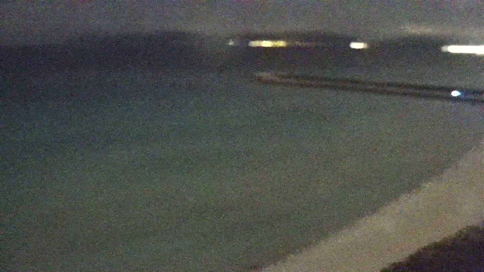 A dark, blurry nighttime view of a body of water with distant lights on the horizon.