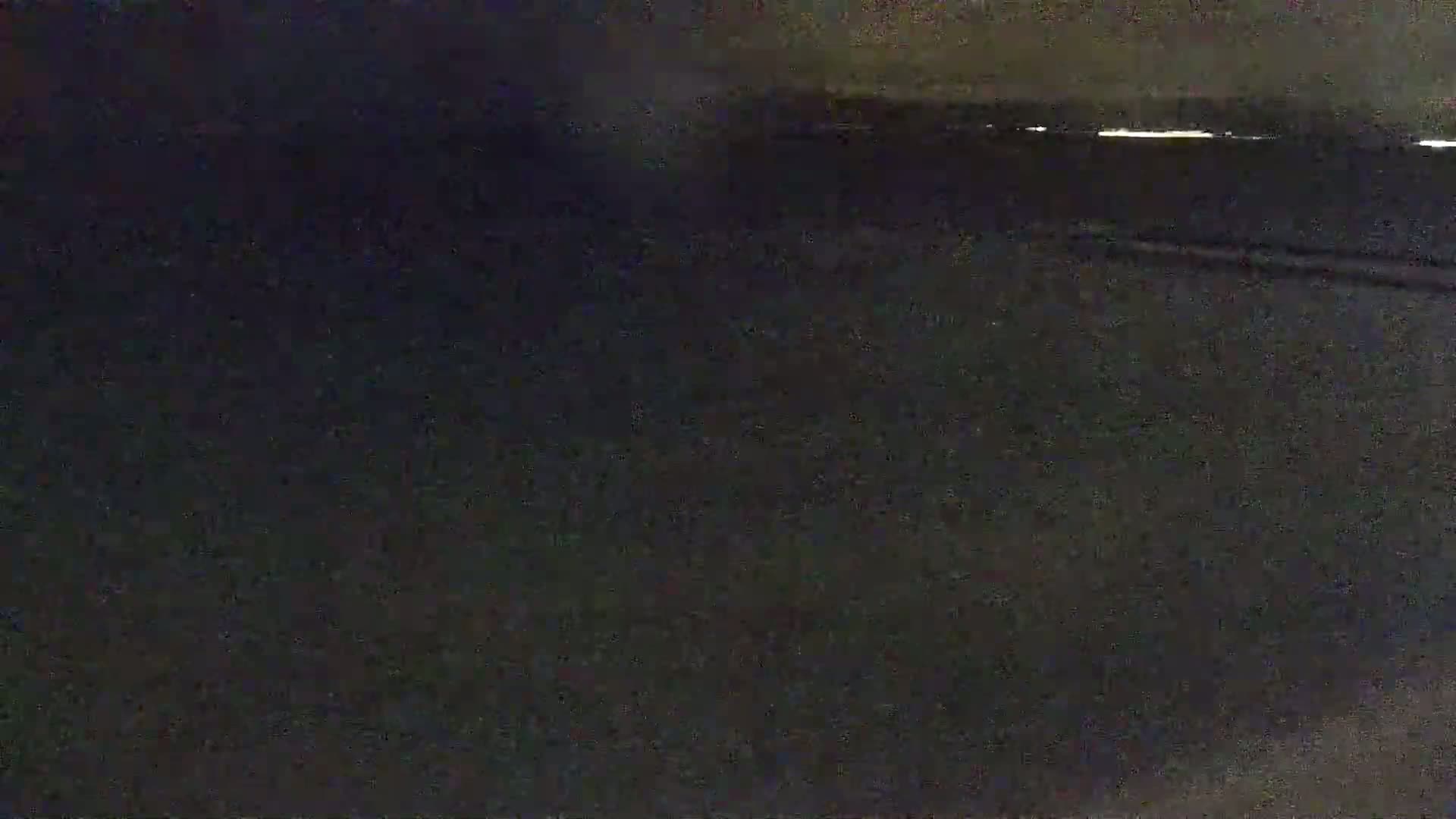 A dark, nighttime scene shows a mostly obscured flat surface with a faint light source in the distance.