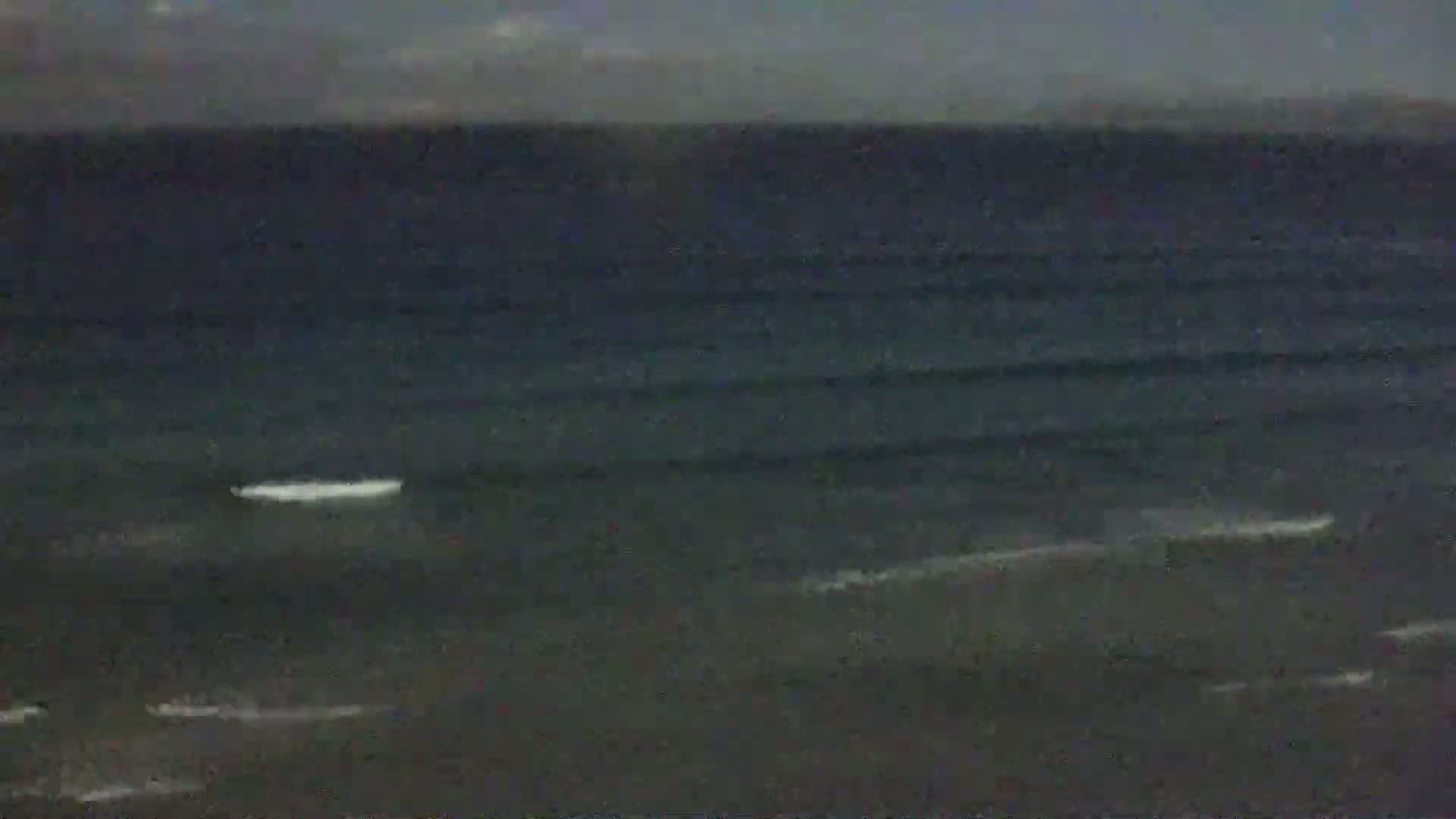 A dark ocean with small waves under an overcast sky.