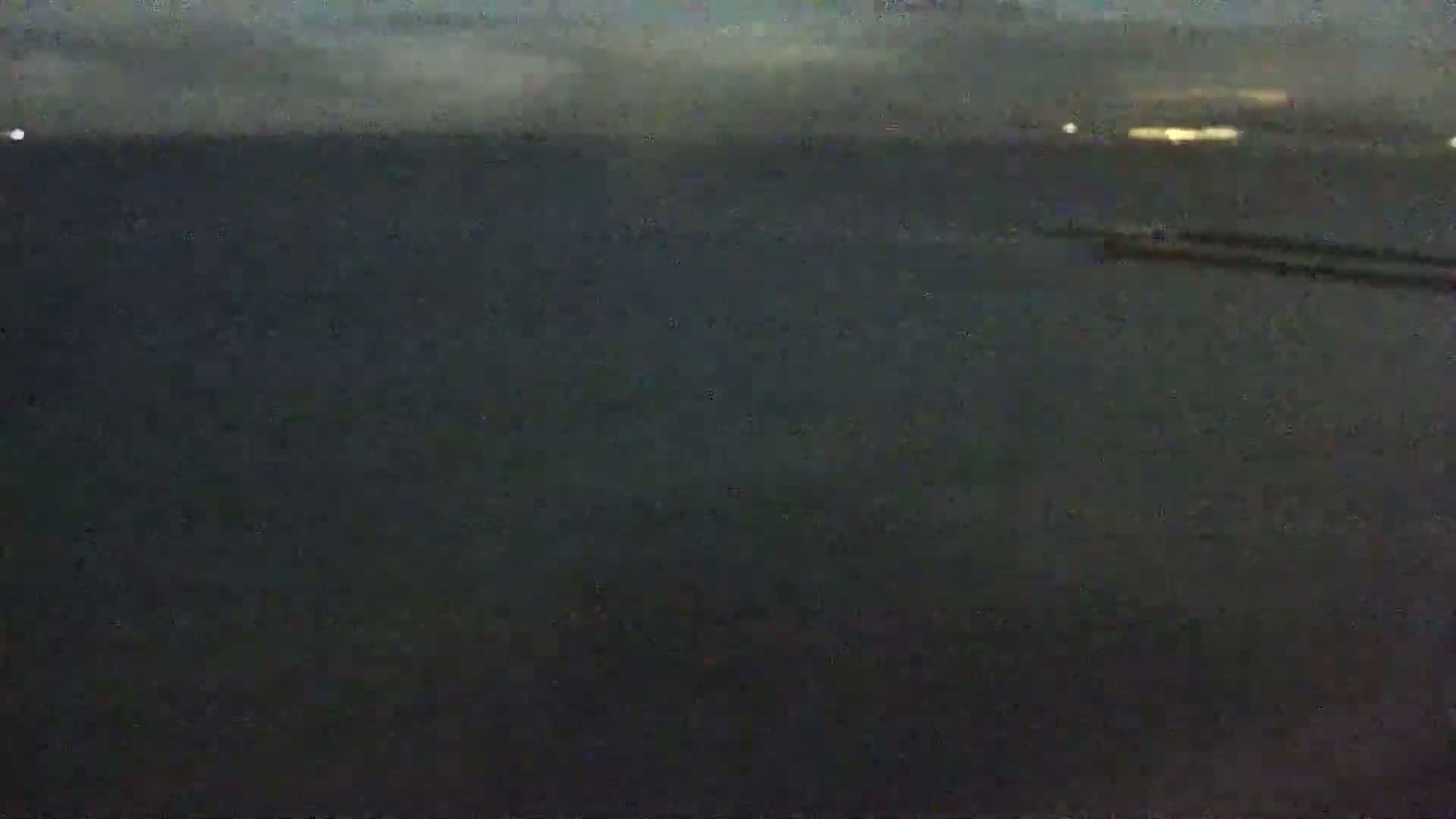 A dark body of water is shown under an overcast sky at night, with a dark object visible on the water's surface in the distance.