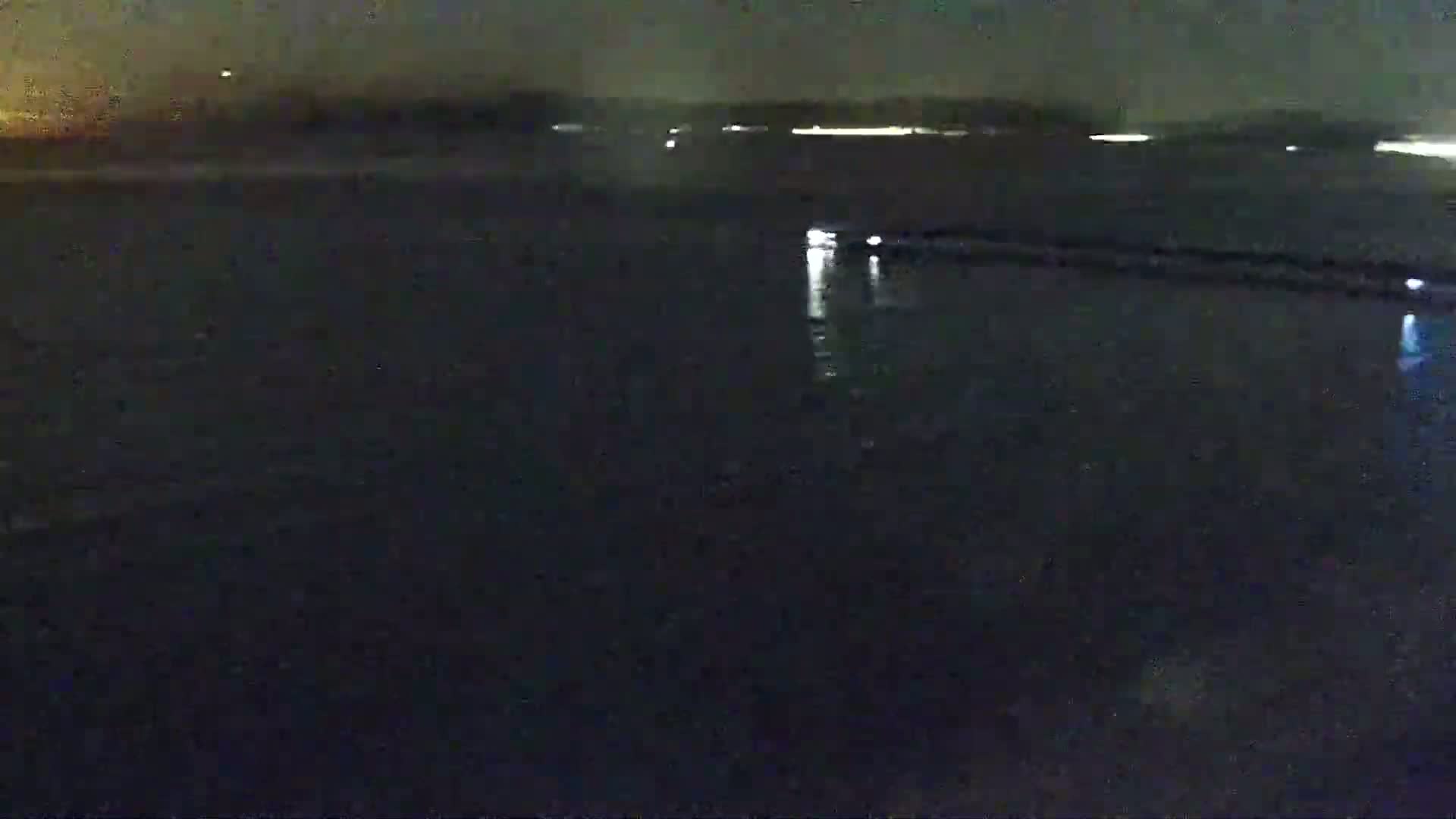 A dark, nighttime view of a body of water with faint lights visible on the far shore.