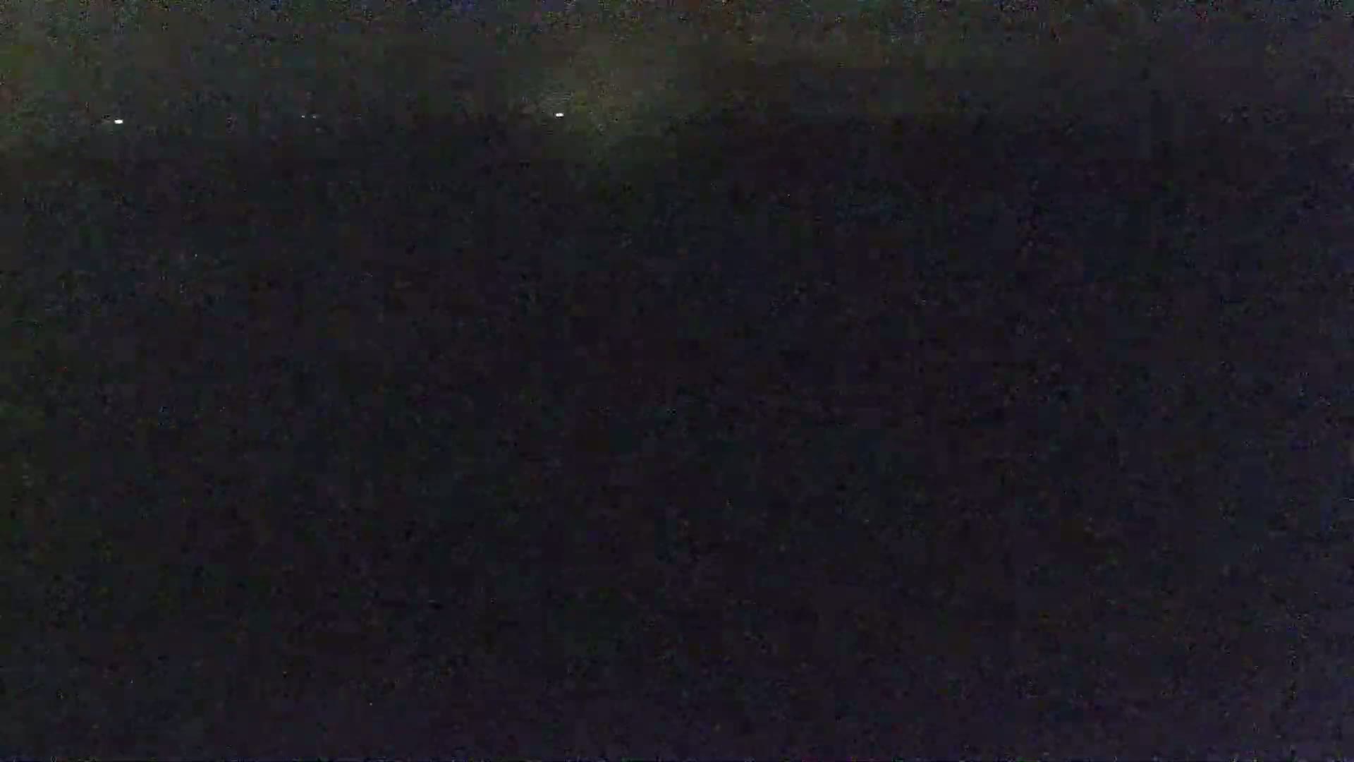 The image shows a dark, nighttime scene with a few faint lights in the distance.