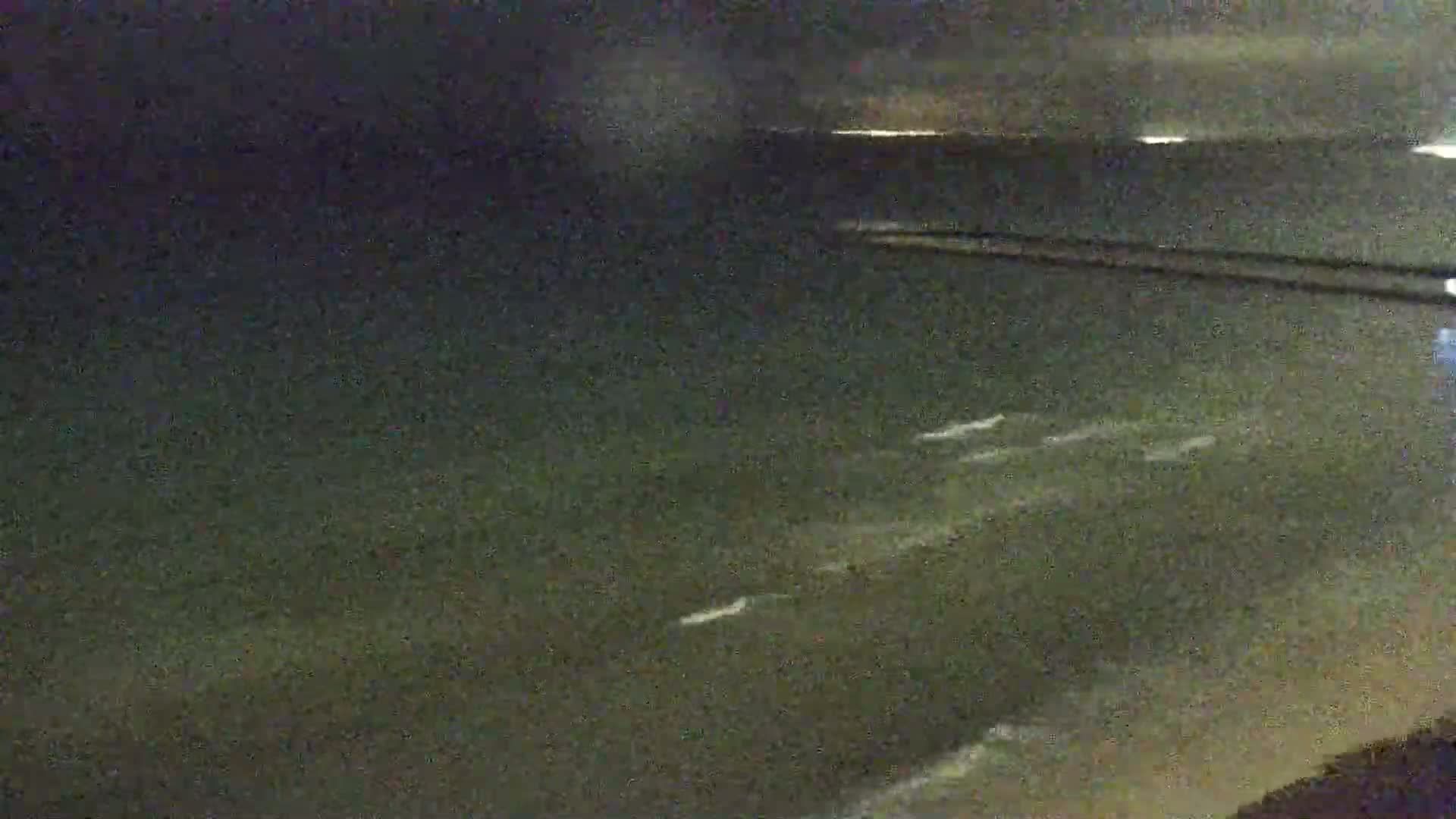 A dark, nighttime view of a body of water with small waves visible under a dark sky.